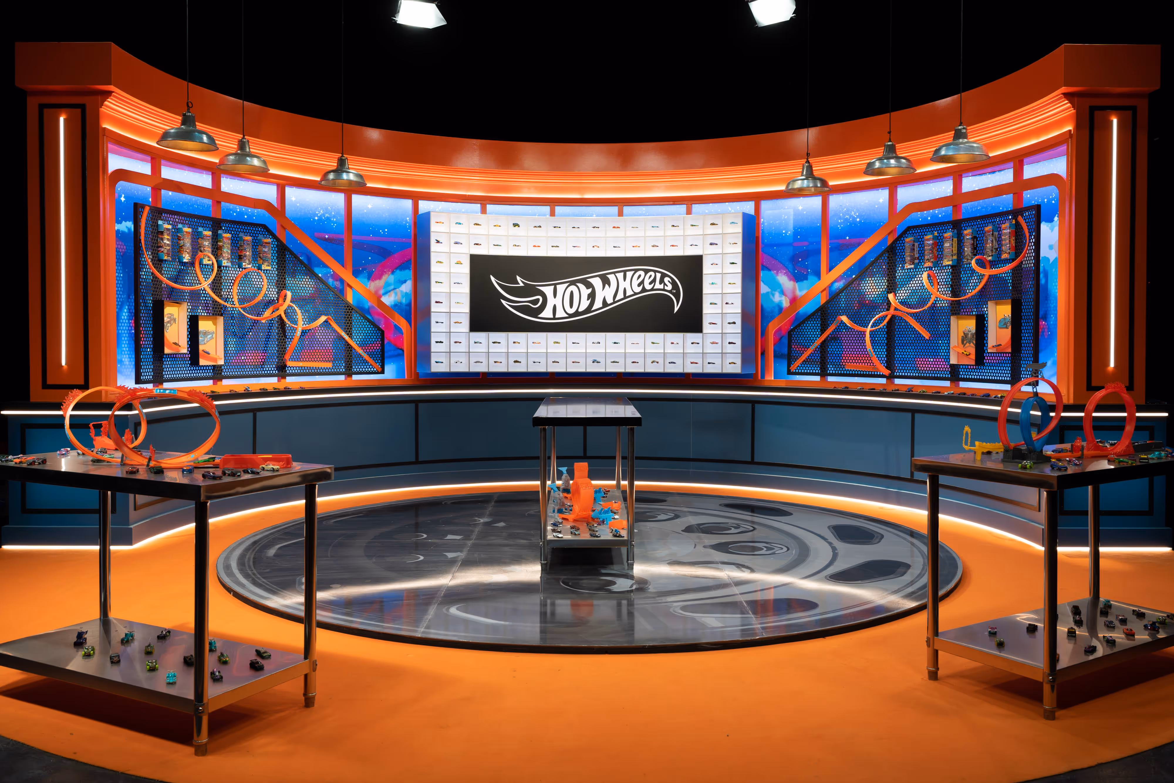 The vibrant Hot Wheels set, with winding tracks and cars, is dramatically lit beneath a bold logo displayed on the main screen.