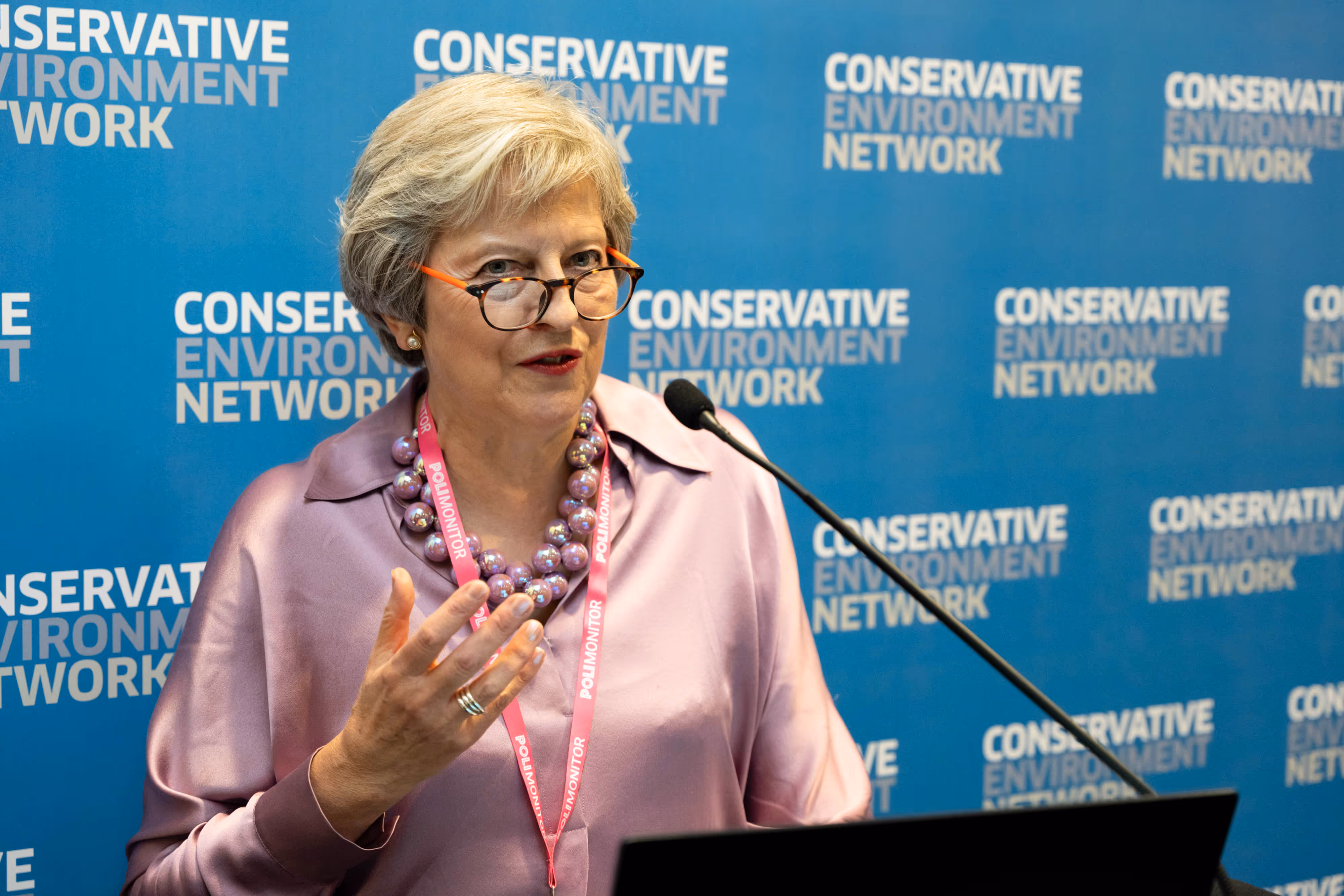 Theresa May MP speaks at a lectern in front of a Conservative Environment Network backdrop.