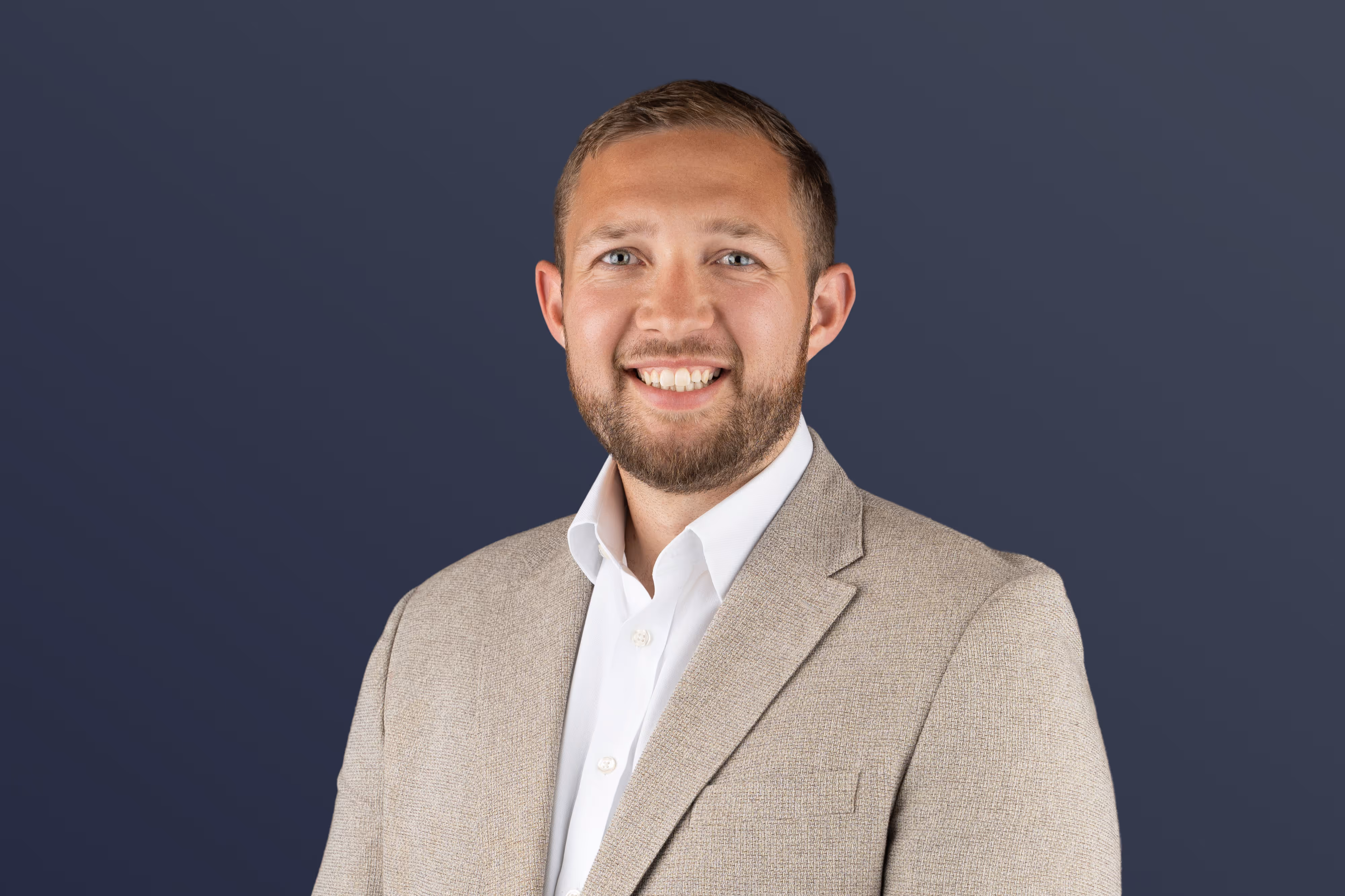 An employee photo of a man in a suit in front of a blue background with a gradient.