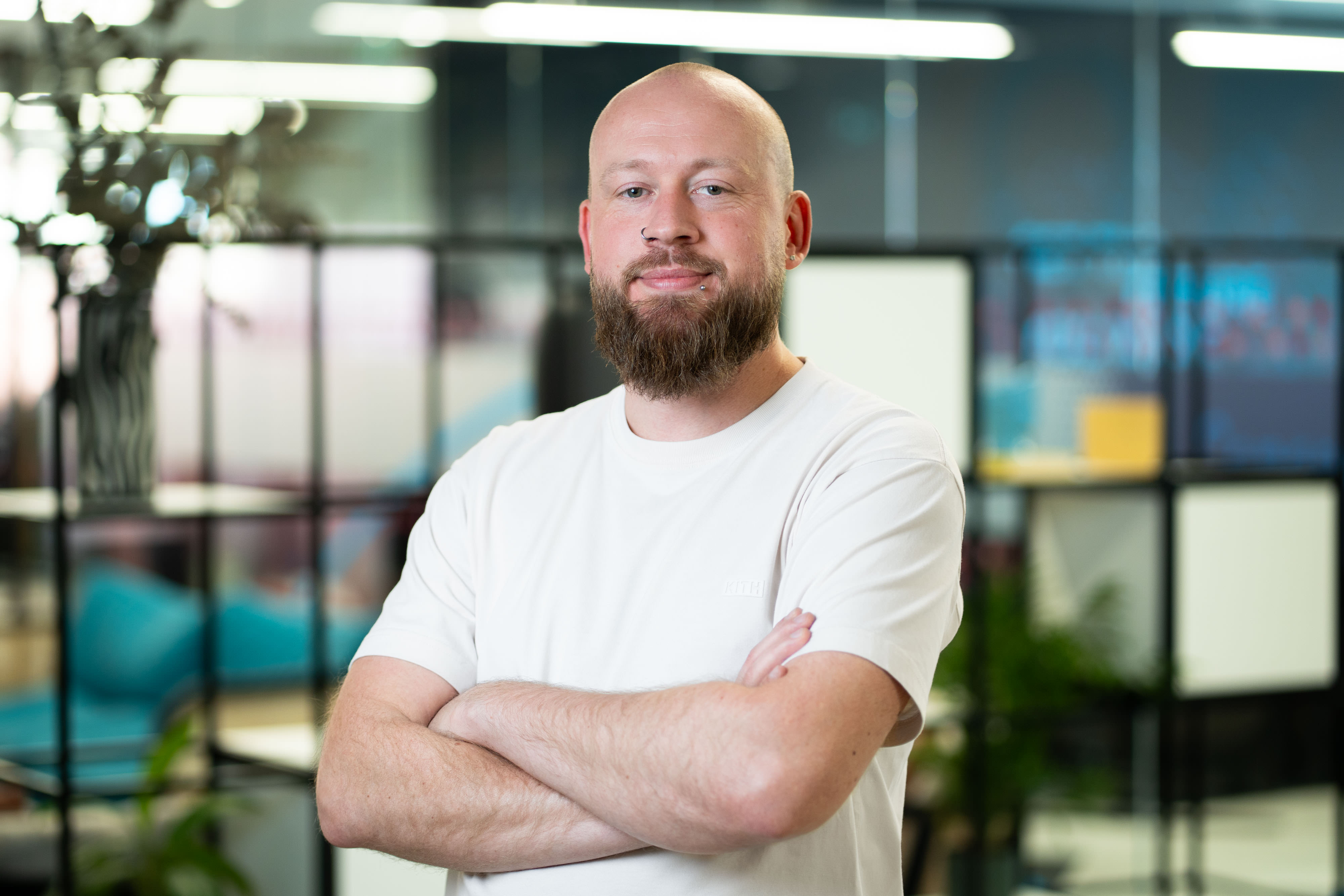 A man with beard and moustache wearing a white shirt posing for a portrait in a Manchester co-working space.