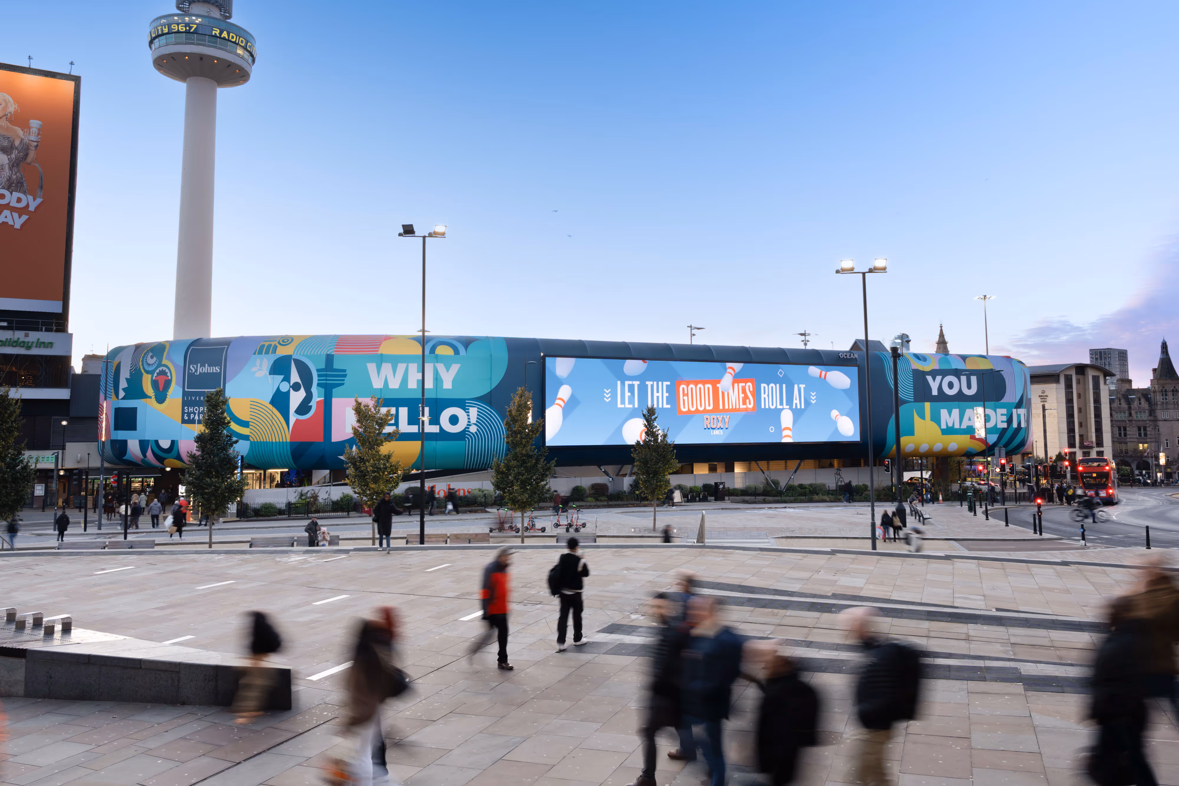 A colourful building wrap with slogans near a busy pedestrian area in Liverpool.