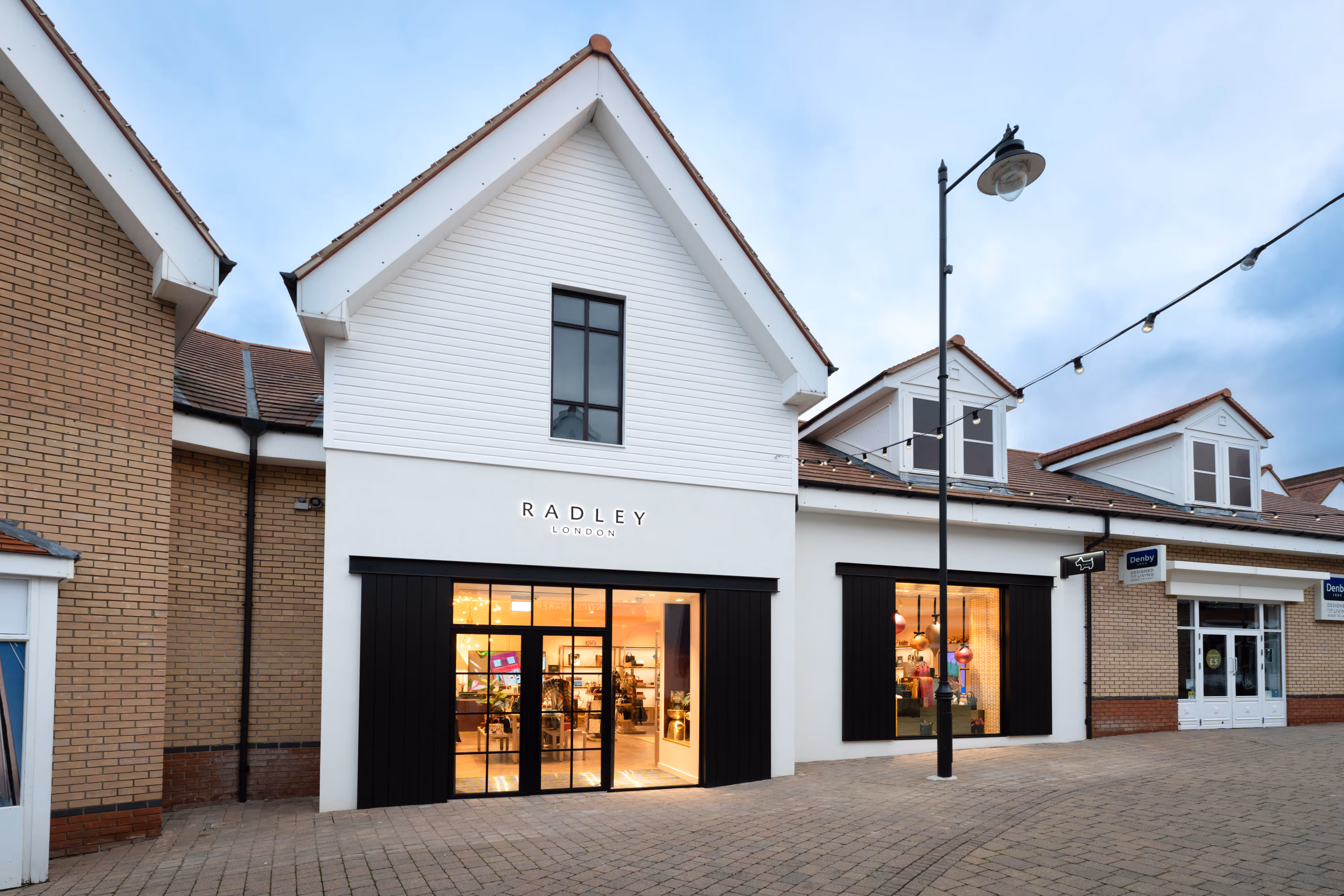 Radley London shop with large windows and black trim in a modern shopping centre, seen on a cloudy day.