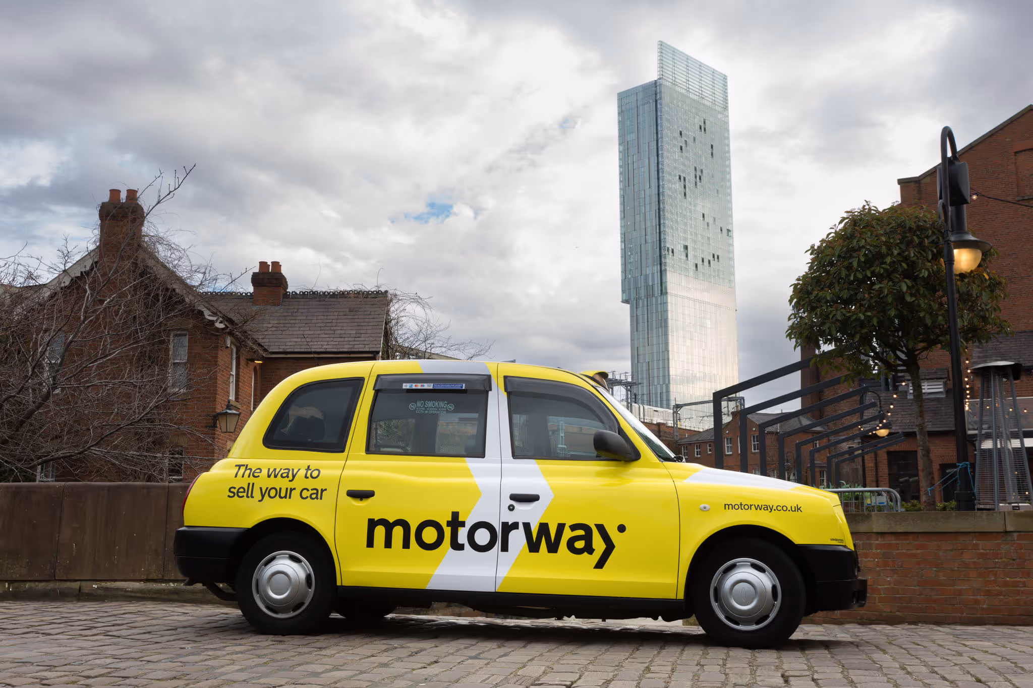 A branded black cab wrapped in yellow with a black logo and tagline on it.