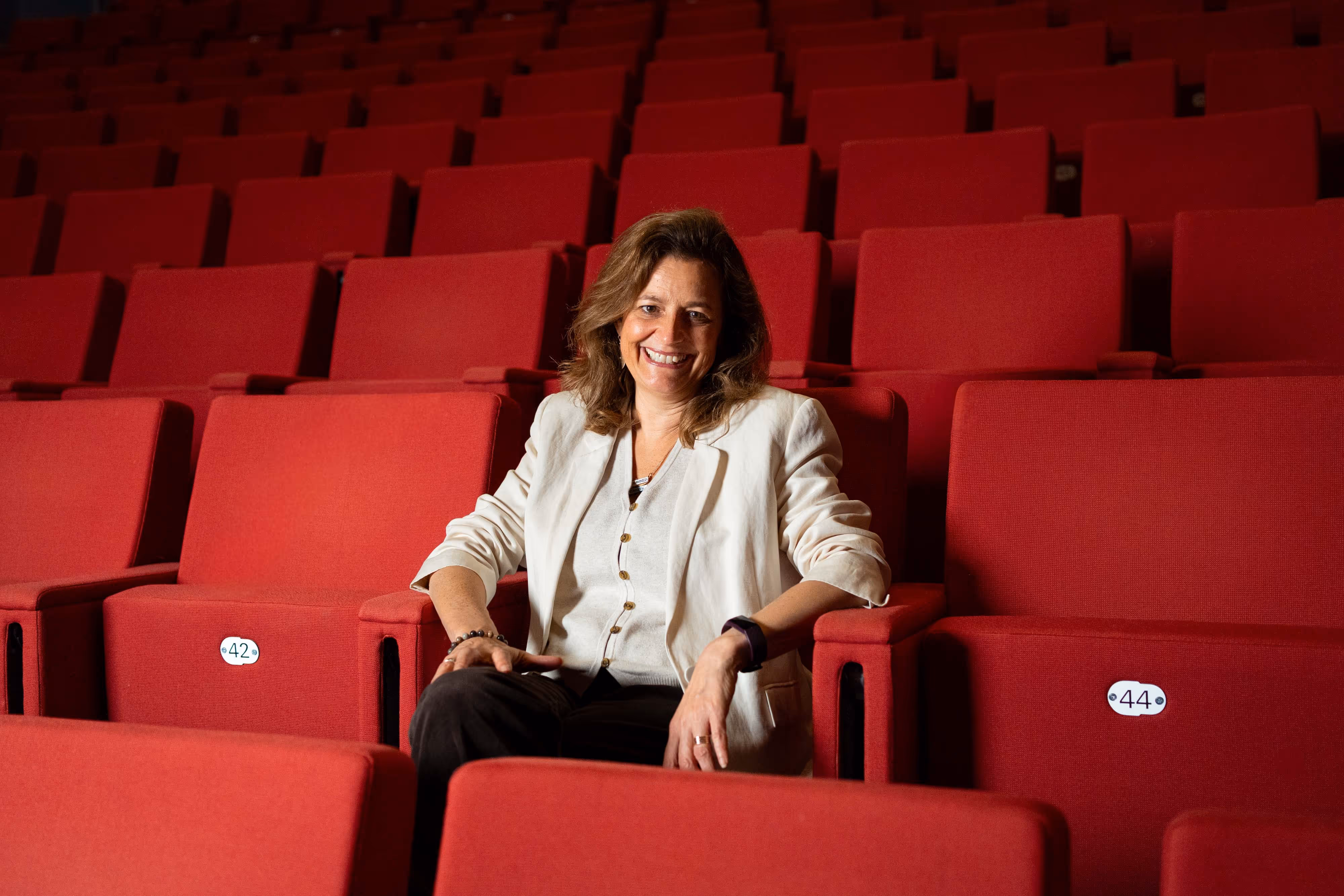 A portrait of a CEO sitting in a seat in an empty theatre.