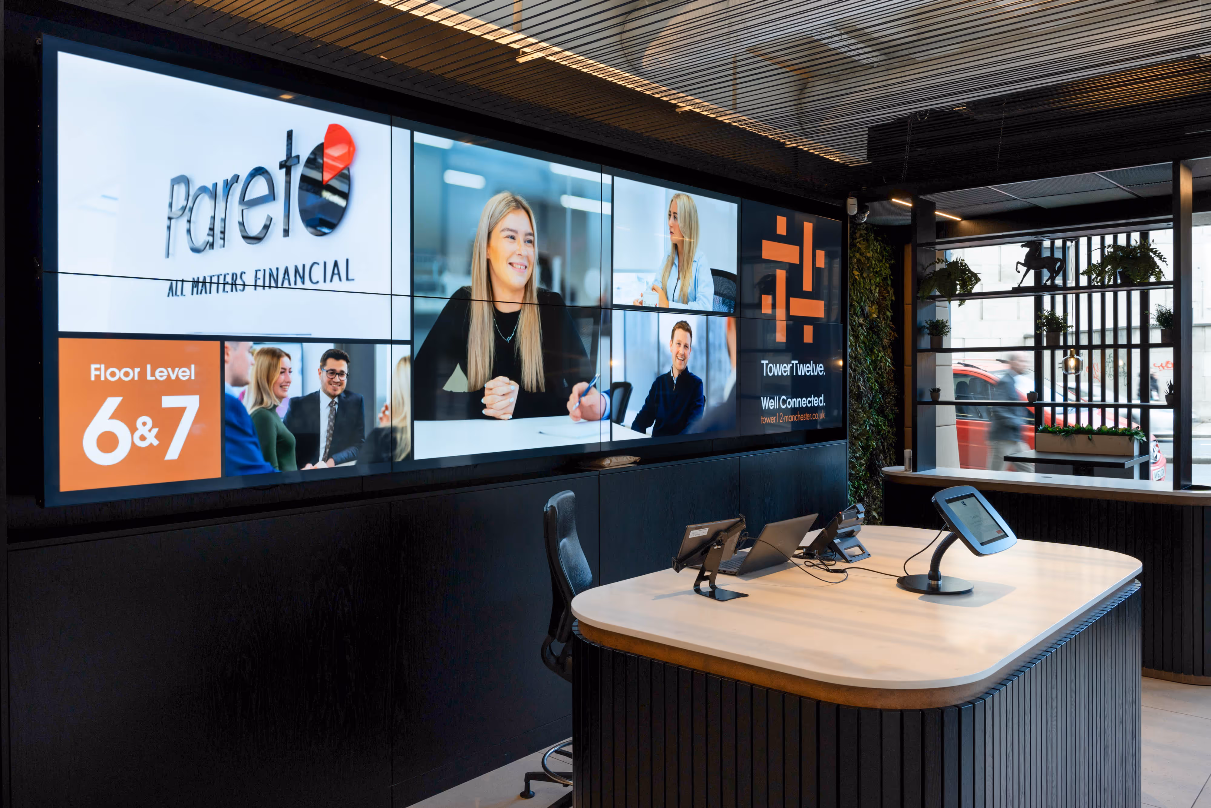 A modern office foyer with photography of an investment firm shown on a large screen.