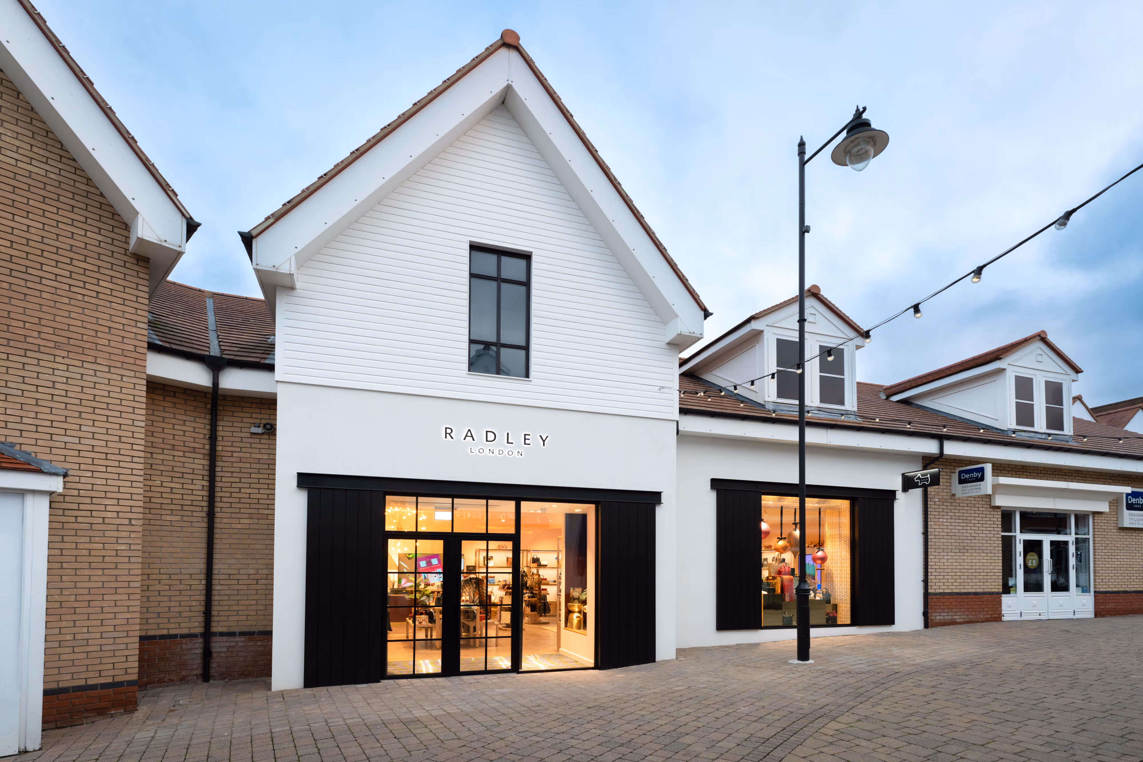 Capturing the Radley London shopfront, showcasing expansive windows and a brick walkway in an outdoor shopping centre setting.