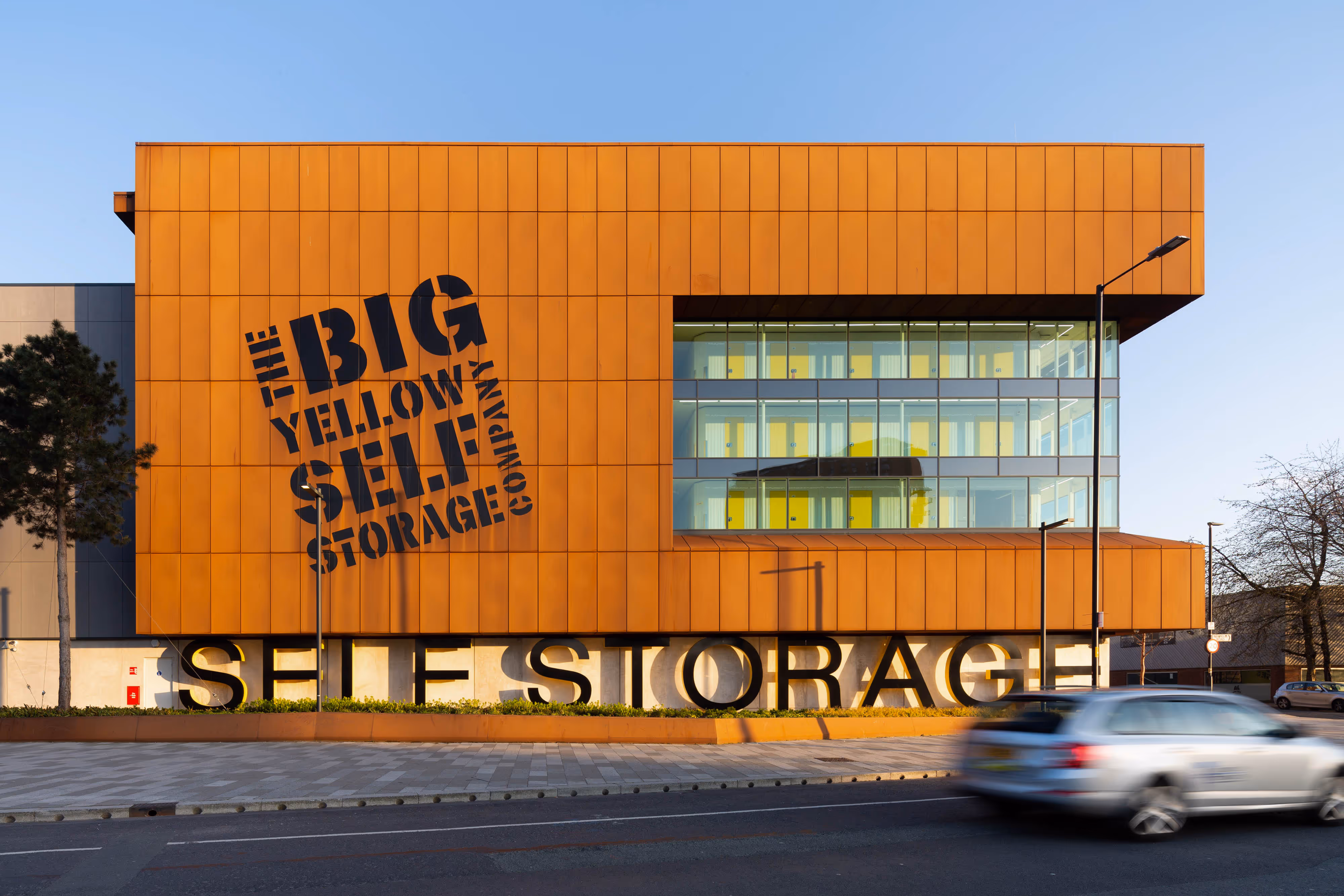 Capturing a bold, modern orange self-storage facility with striking "SELF STORAGE" lettering and The Big Yellow signage displayed.