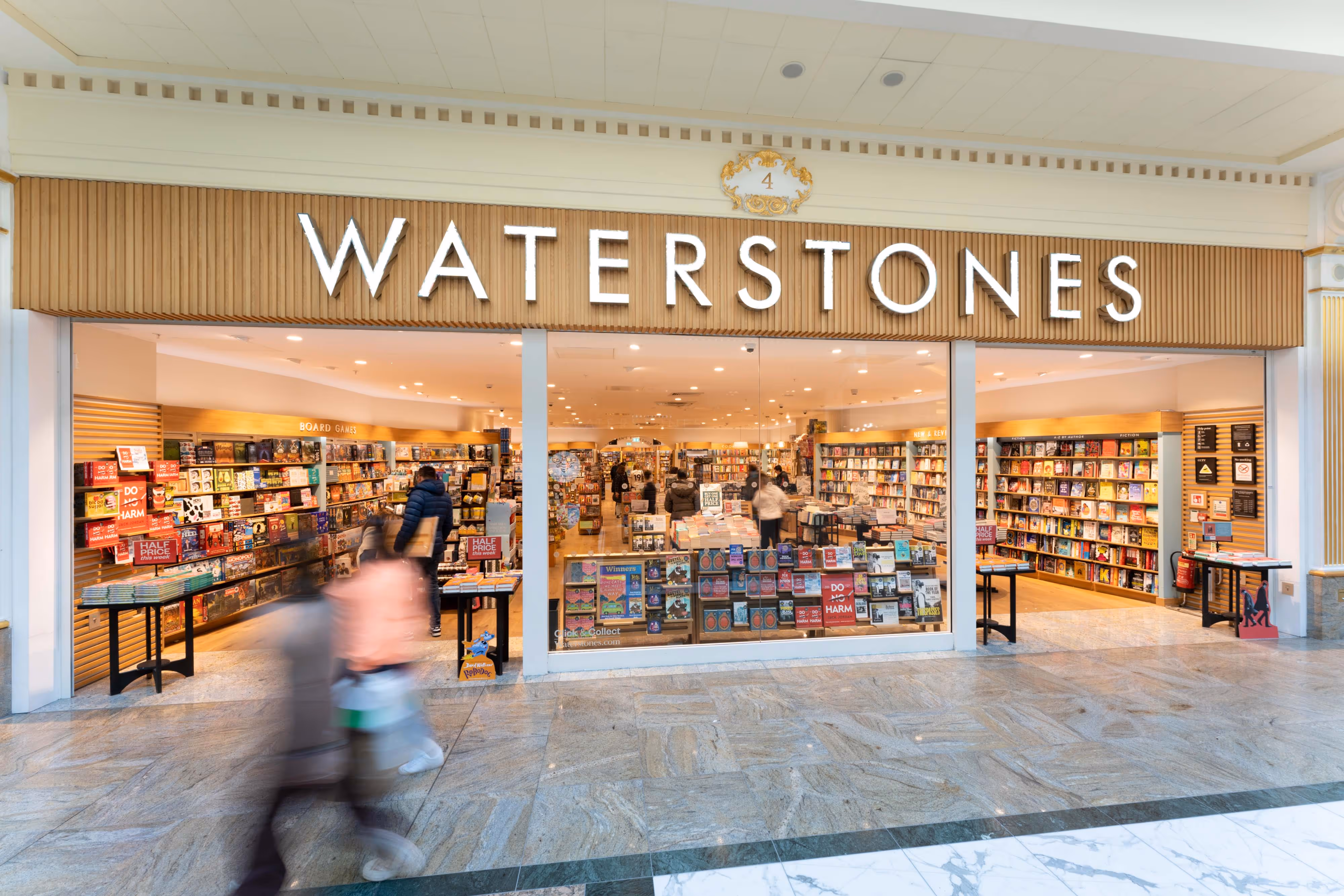 Wide shot of Waterstones shopfront capturing foot traffic outside and book-filled shelves visible through the large glass windows.