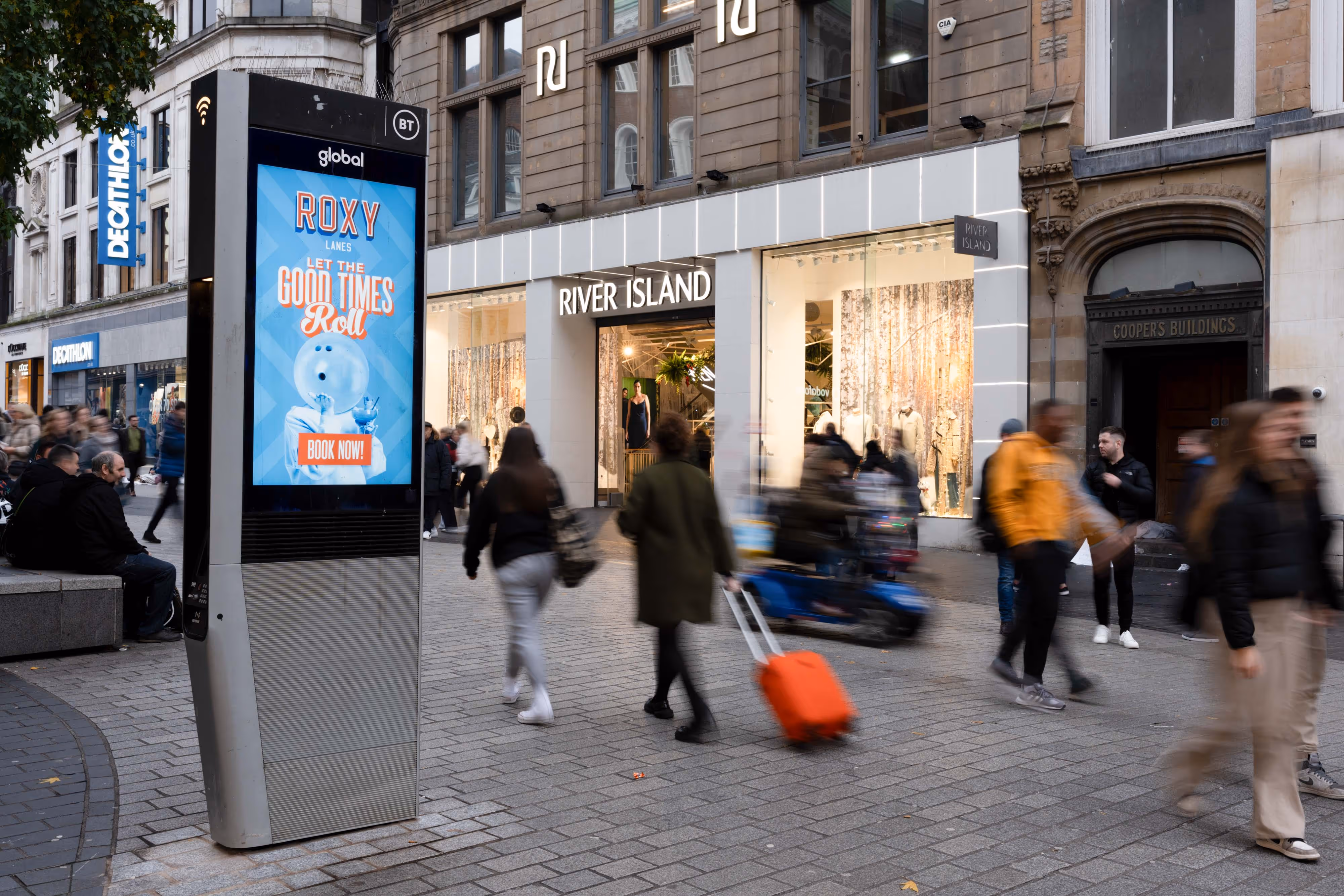 Capturing the energy of urban life, I photograph a digital billboard by River Island as pedestrians blur past in constant motion.