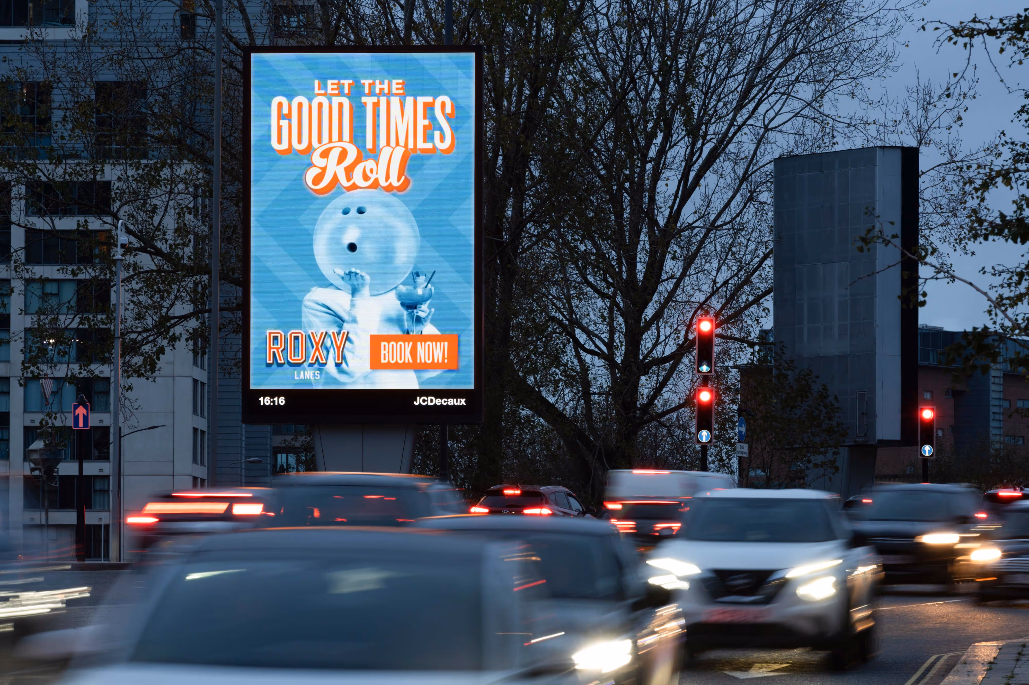 Captured at dusk in Liverpool, the digital billboard stands out over busy city traffic: "Let the Good Times Roll" with bowling ball, pins, and "Book Now.