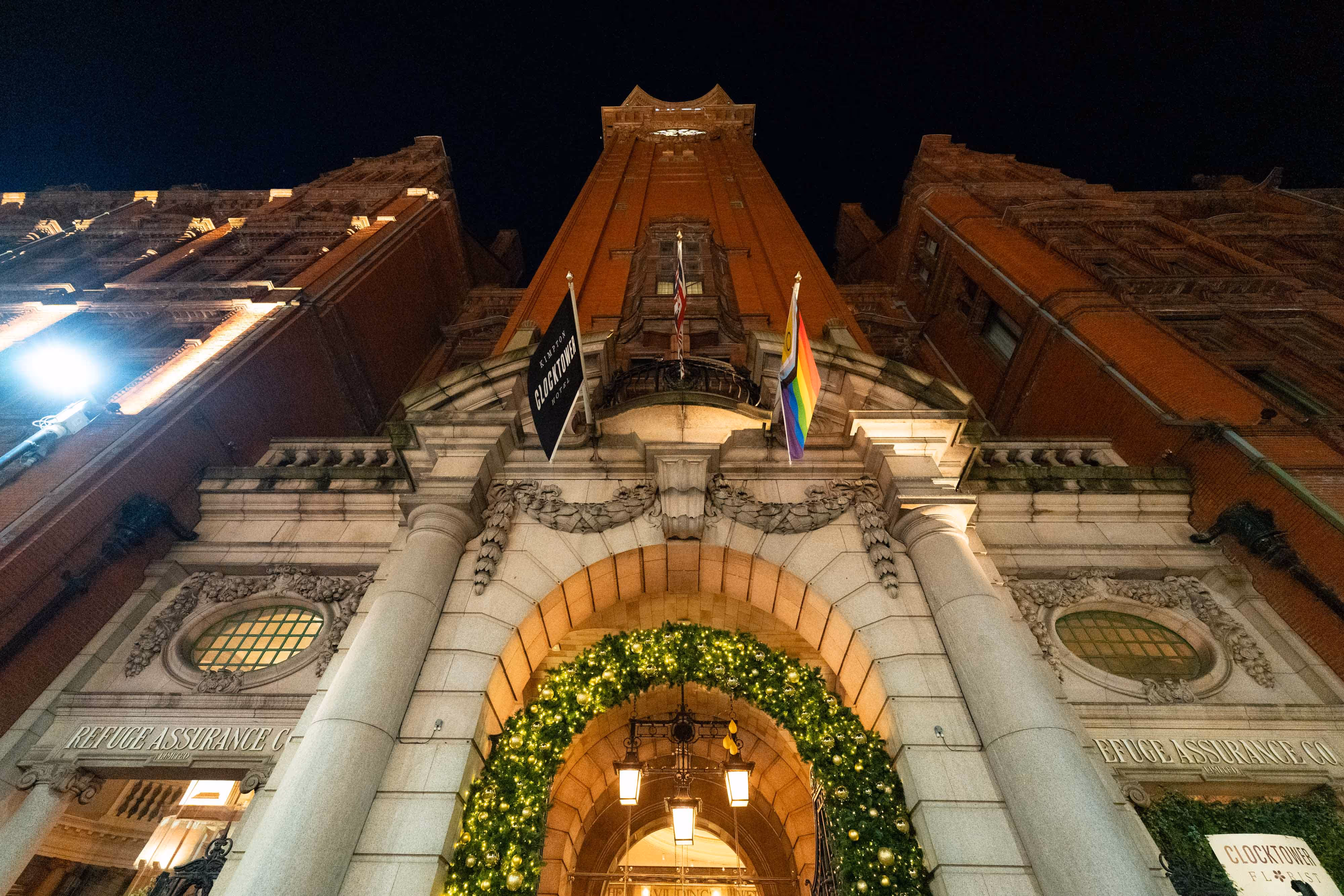 Festive night shot looking up at an impressive building entrance adorned with flags and a green-lit arch.