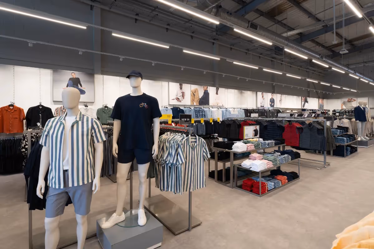 Photographed a Warrington clothing store’s interior showcasing mannequins in casual wear and display tables arranged with folded shirts.	