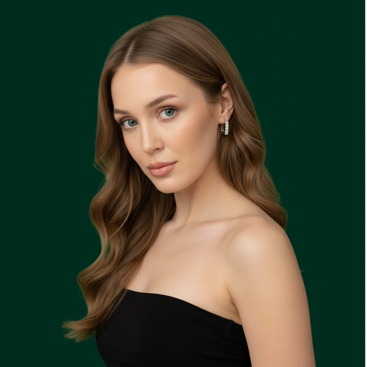 Portrait of a woman with long wavy brown hair, blue eyes, wearing a black strapless top and silver hoop earrings against a dark green background.