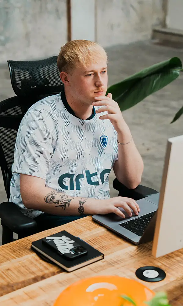 Nick van East Creatives geconcentreerd aan het werk achter zijn computer in de studio, met tatoeage zichtbaar op zijn arm.