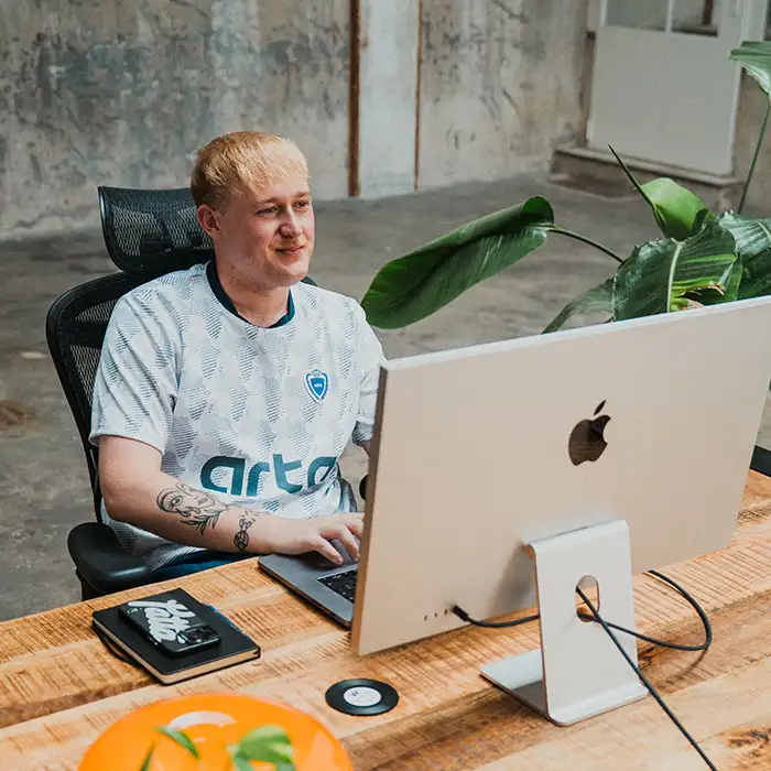 Nick van East Creatives achter zijn bureau met iMac, geconcentreerd aan het werk in de creatieve studio.