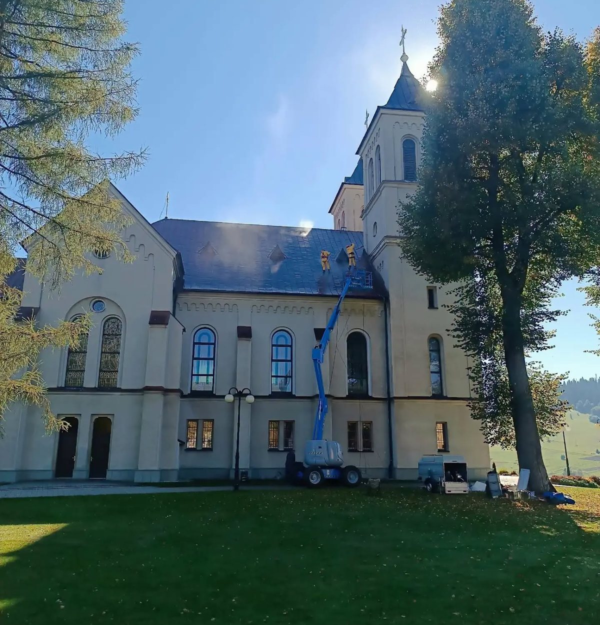 Farský kostol v Zákamennom počas obnovy – pracovníci natierajú strechu z pracovnej plošiny