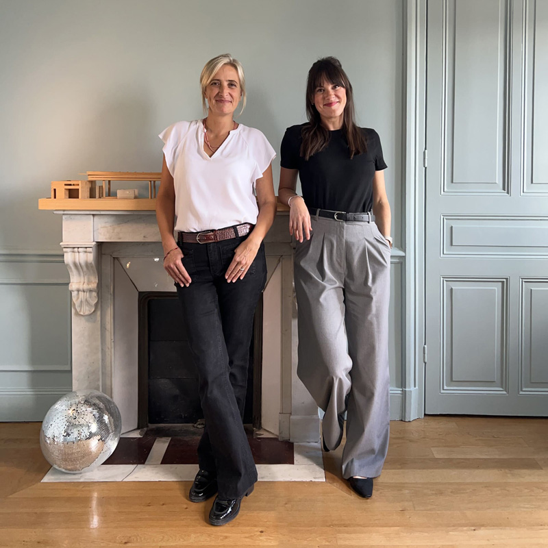 Portrait des deux associées du cabinet d’architecture, posant côte à côte, souriantes, en tenue professionnelle