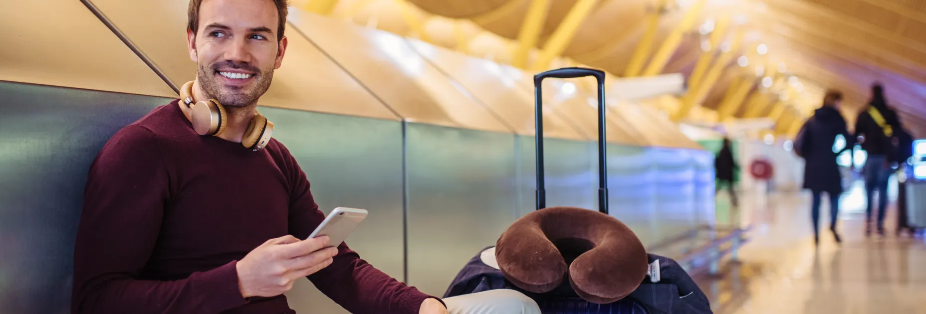 A man sitting on a bench next to a bag of luggage.