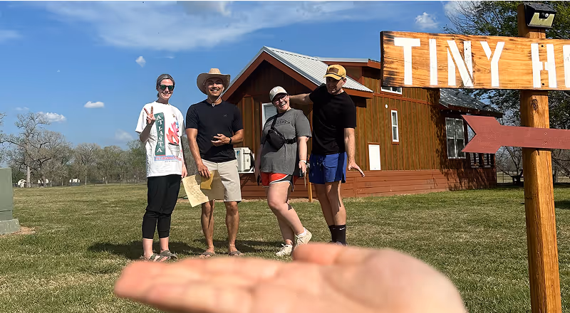 Group standing outside near a “Tiny House” sign on a sunny day