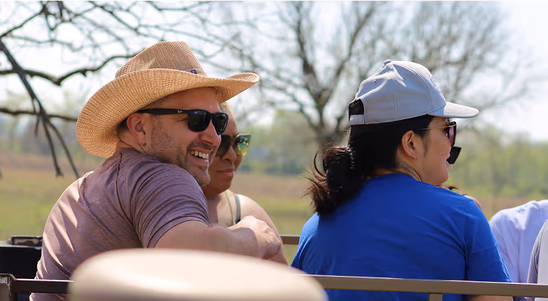Two people wearing hats sitting outdoors and talking on a sunny day