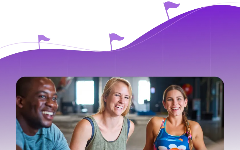 Group of three people in a gym smiling after a workout, symbolizing teamwork and fitness.