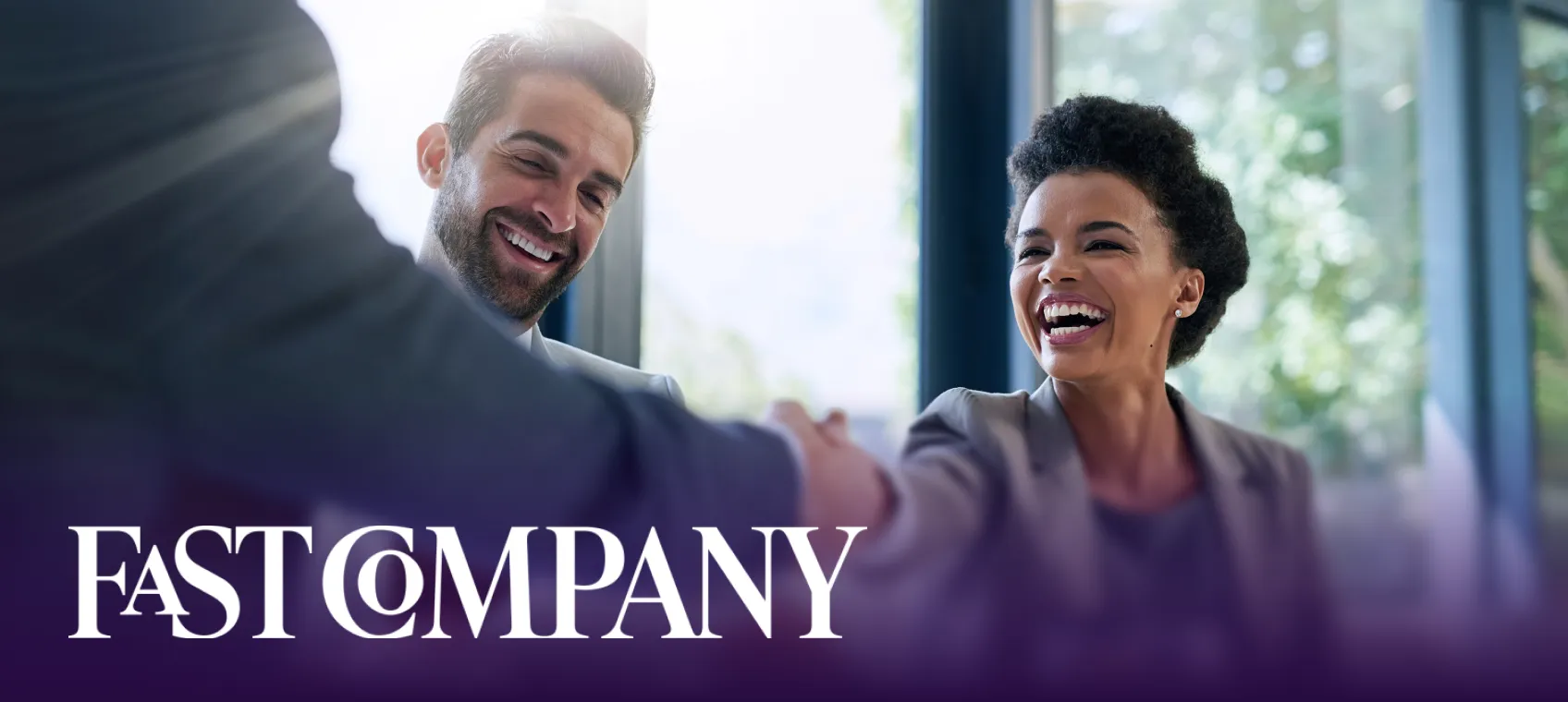 Smiling man and woman in business attire shaking hands in a bright office setting with Fast Company logo overlay.