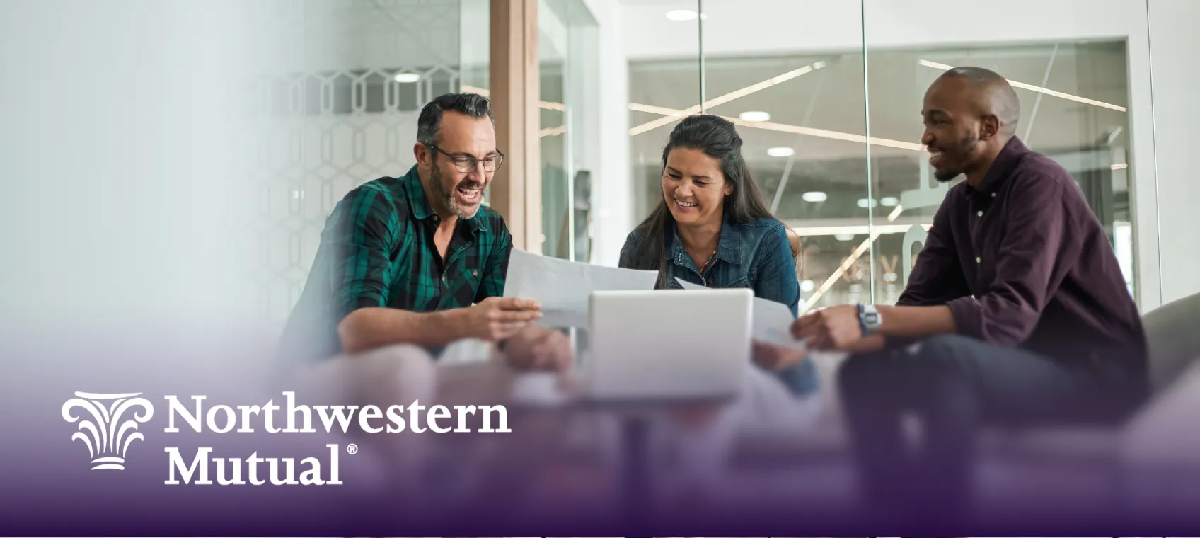 Three colleagues smiling and discussing documents around a laptop in a modern office with a Northwestern Mutual logo overlay.