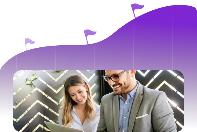 Two professionals smiling while looking at a laptop, set against a background with a purple graph and flags indicating progress.