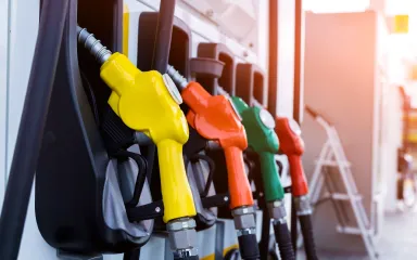 Yellow, red, and green fuel nozzles lined up at a gas station pump.