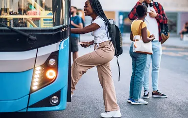 Young woman boarding a blue city bus while two other people wait nearby.