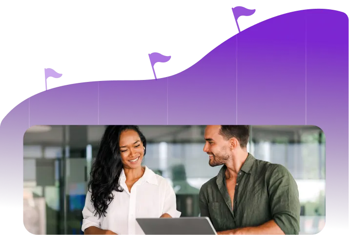 Smiling man and woman looking at laptop in a modern office setting.