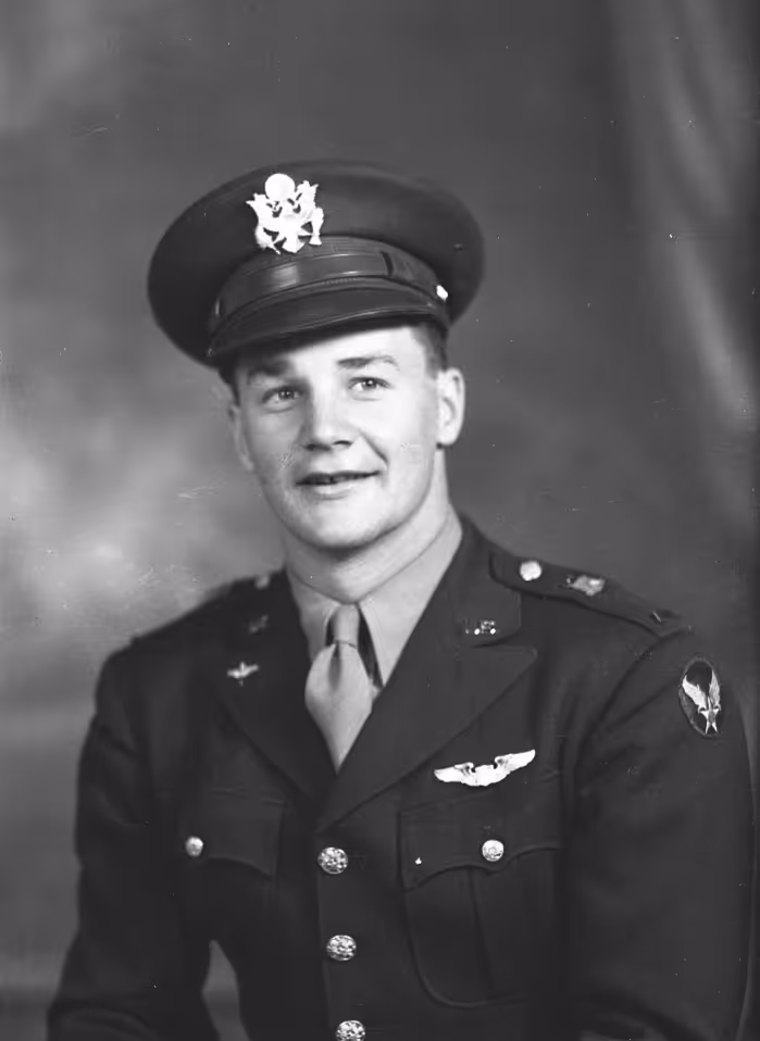 Black and white portrait of a young man in a military uniform with pilot wings and a peaked cap.