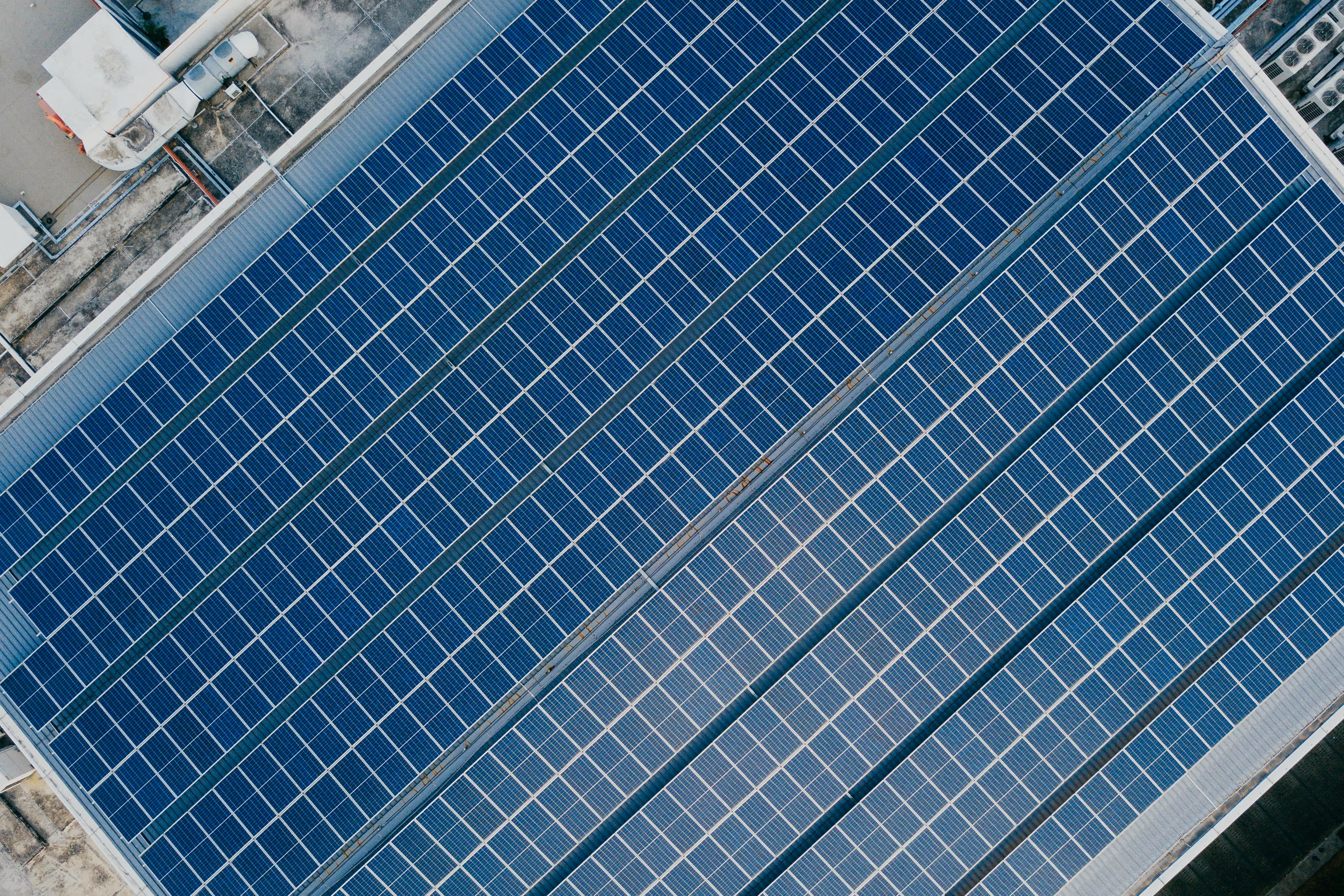 Zonnepanelen op het dak van een bedrijfspand, gezien van boven.