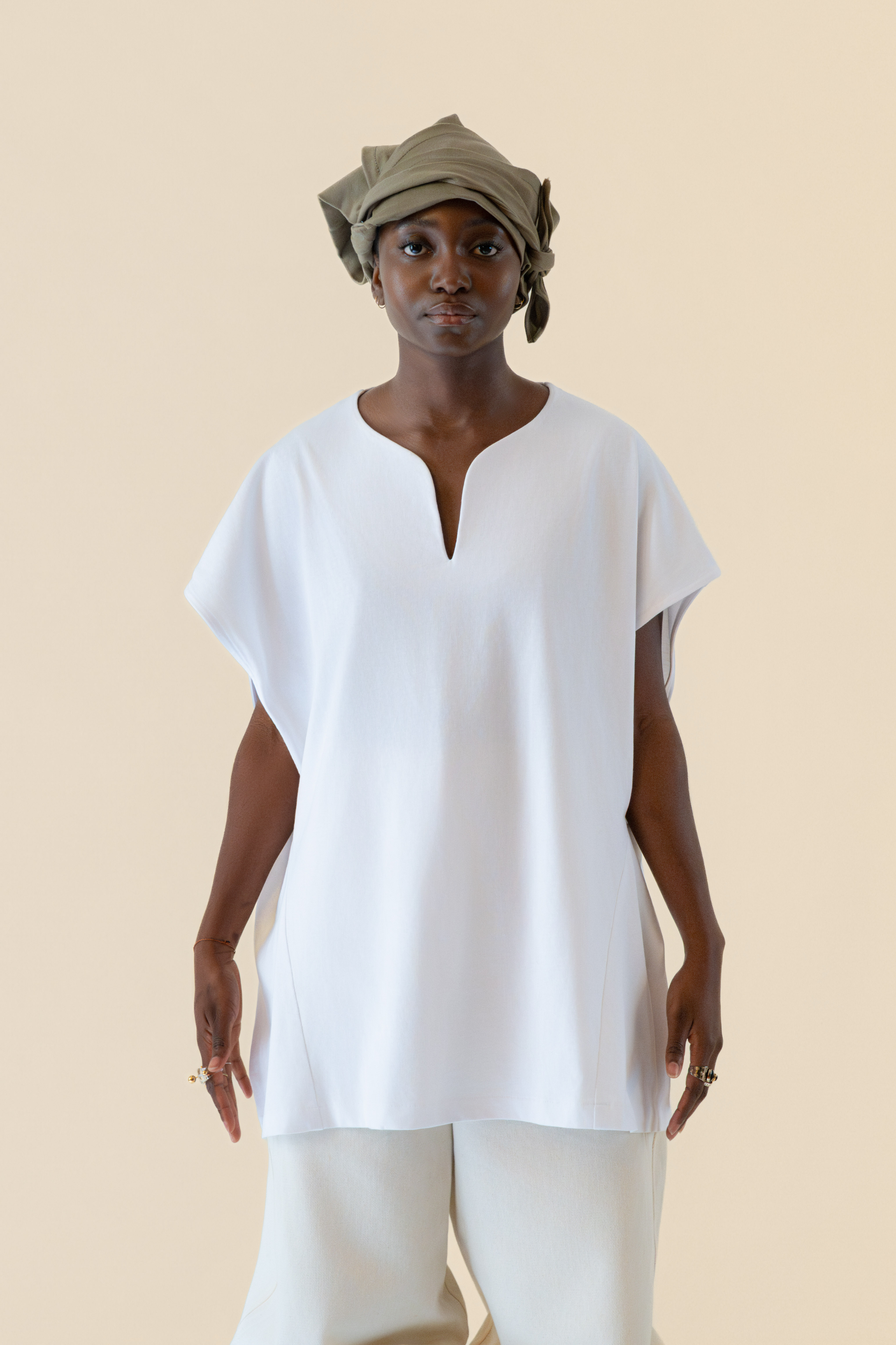 Model wearing white U-neck tunic in soft cream light, Oniri editorial aesthetic