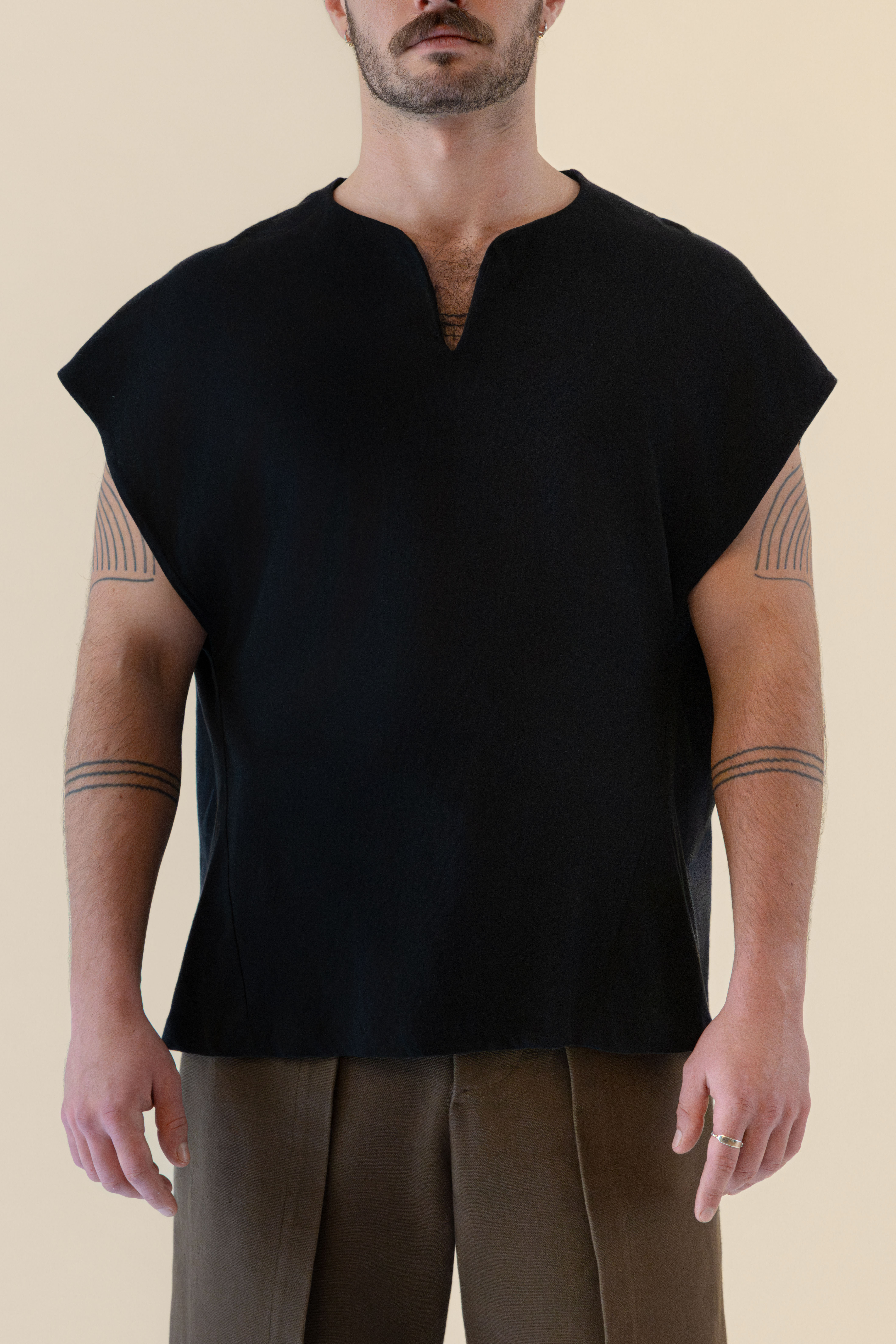 Front half-body view of male model wearing the black Light U-neck Tunic with soft warm light, Oniri editorial aesthetic