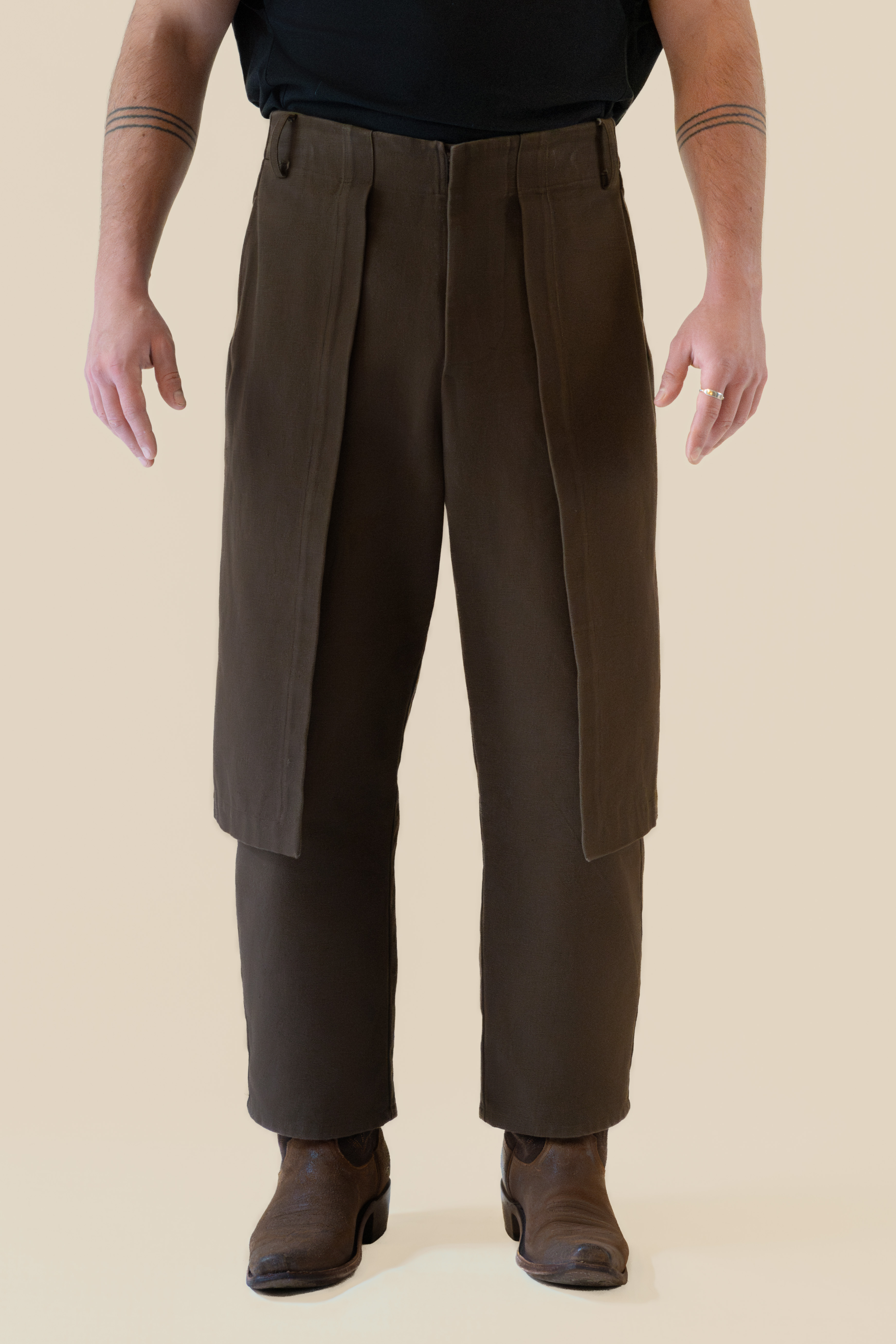 Front view of male model wearing brown Cowboy Pants in soft warm light, Oniri editorial aesthetic