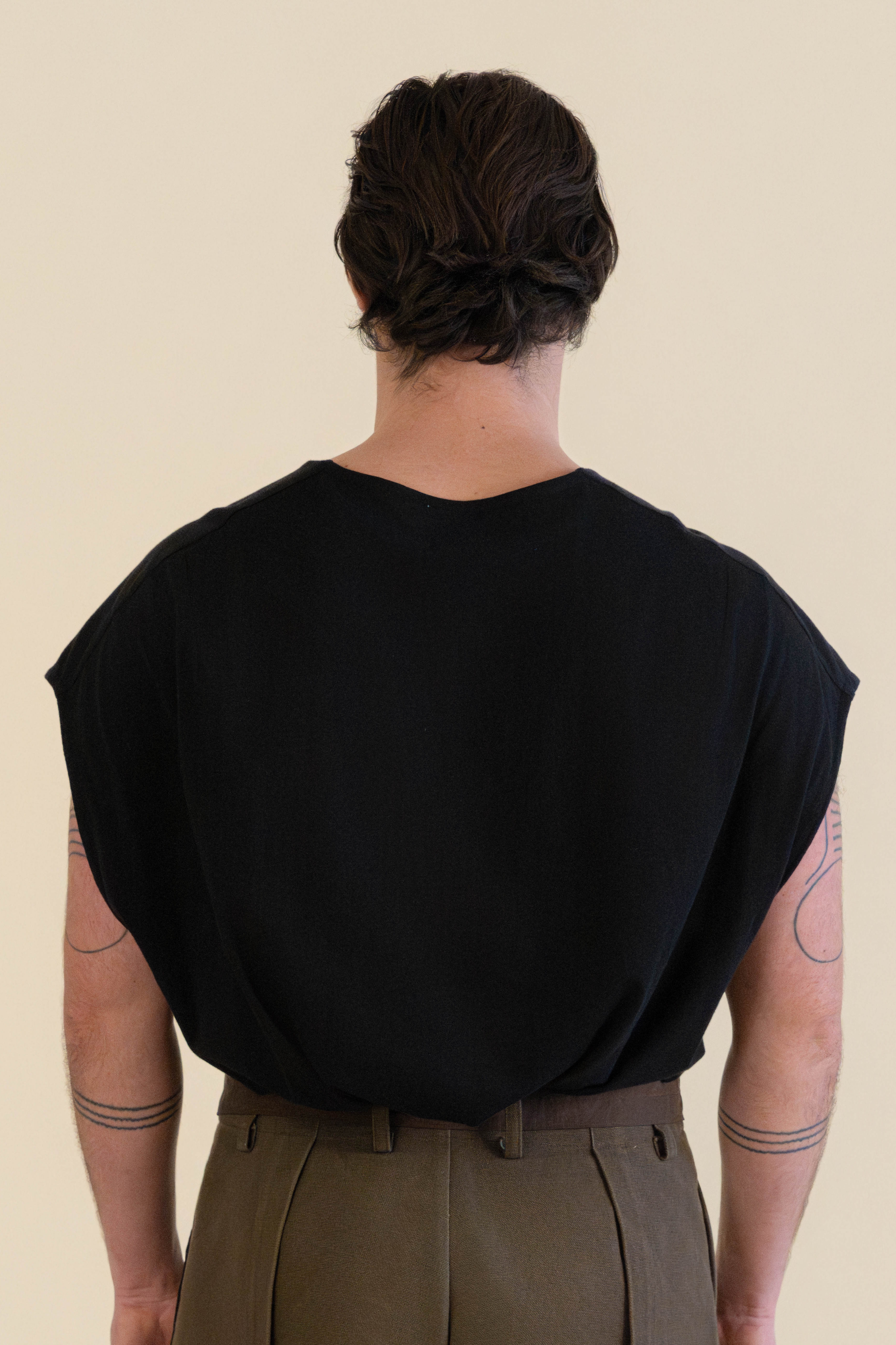 Back view of male model walking away wearing dark Light U-neck Tunic and brown Cowboy Pants in soft warm light, Oniri editorial aesthetic