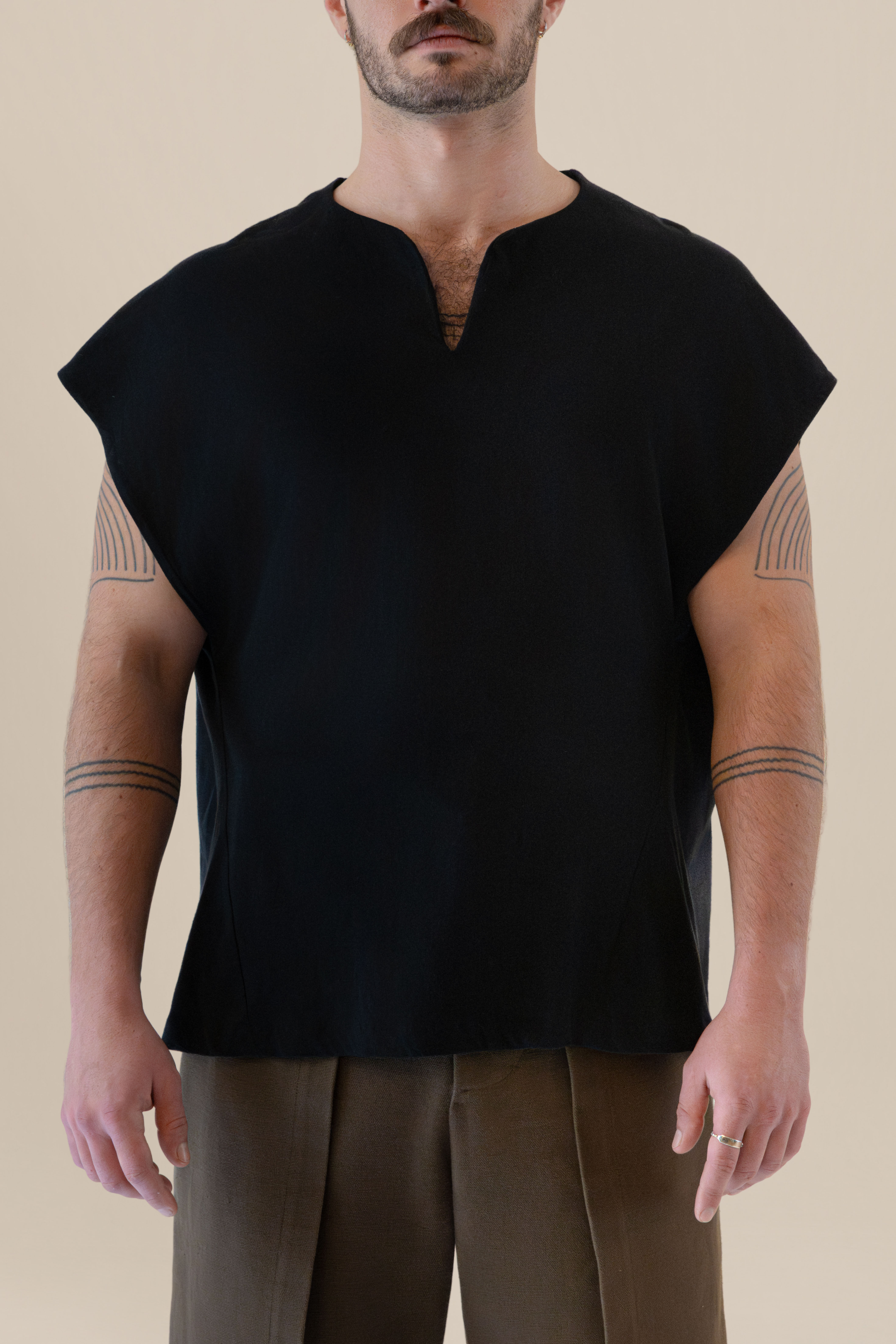 Front half-body view of male model wearing the black Light U-neck Tunic with soft warm light, Oniri editorial aesthetic