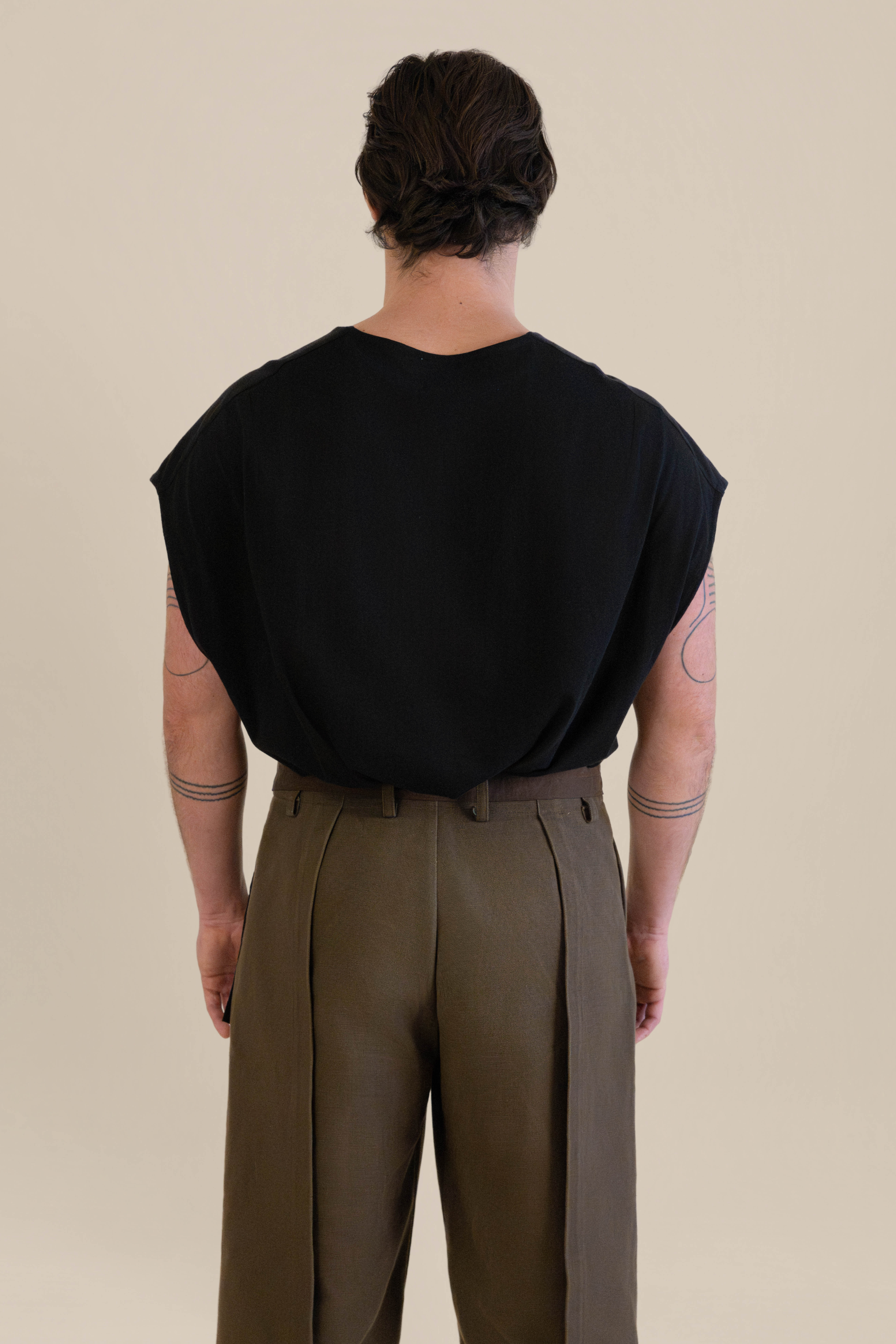 Back view of male model walking away wearing dark Light U-neck Tunic and brown Cowboy Pants in soft warm light, Oniri editorial aesthetic