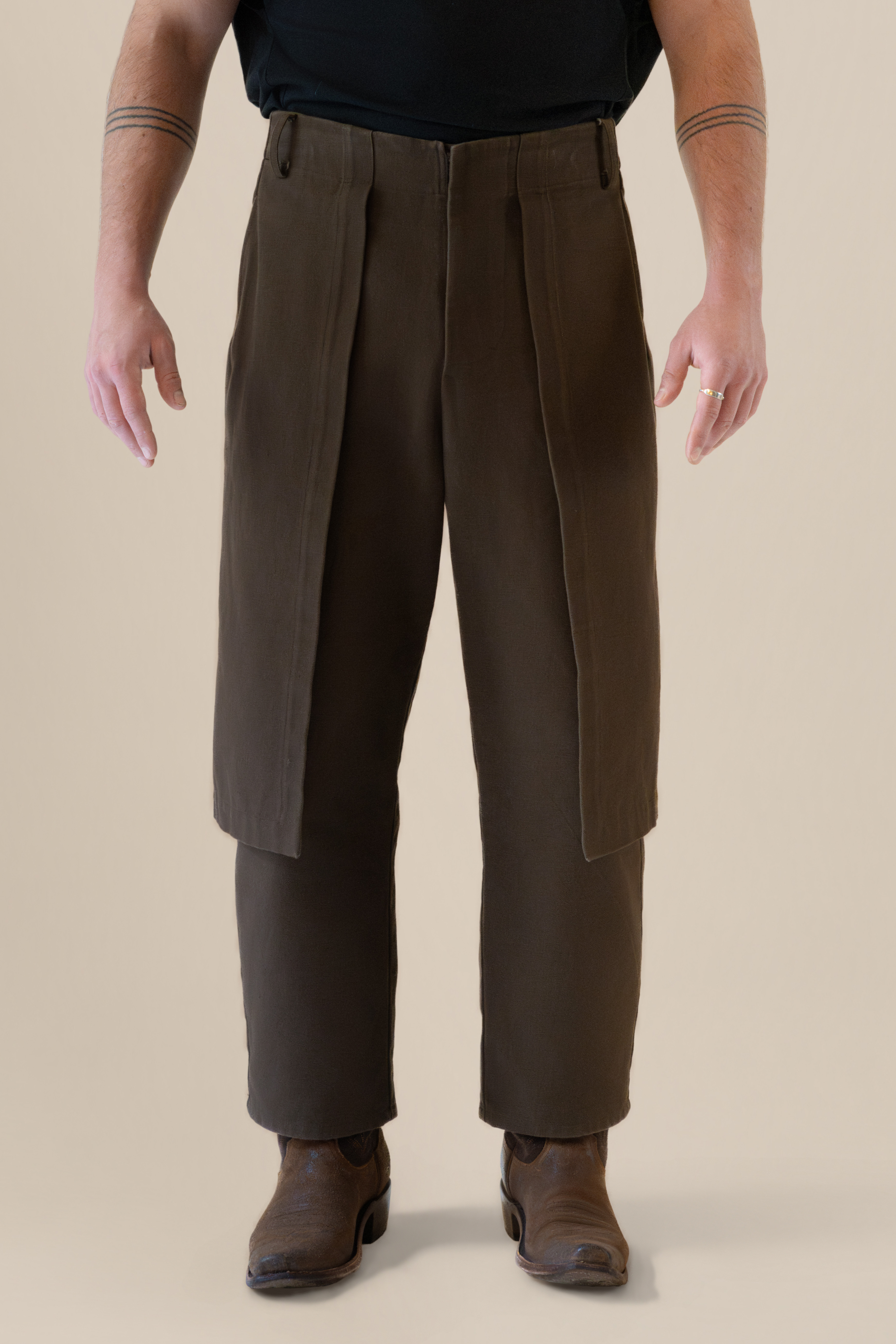 Front view of male model wearing brown Cowboy Pants in soft warm light, Oniri editorial aesthetic
