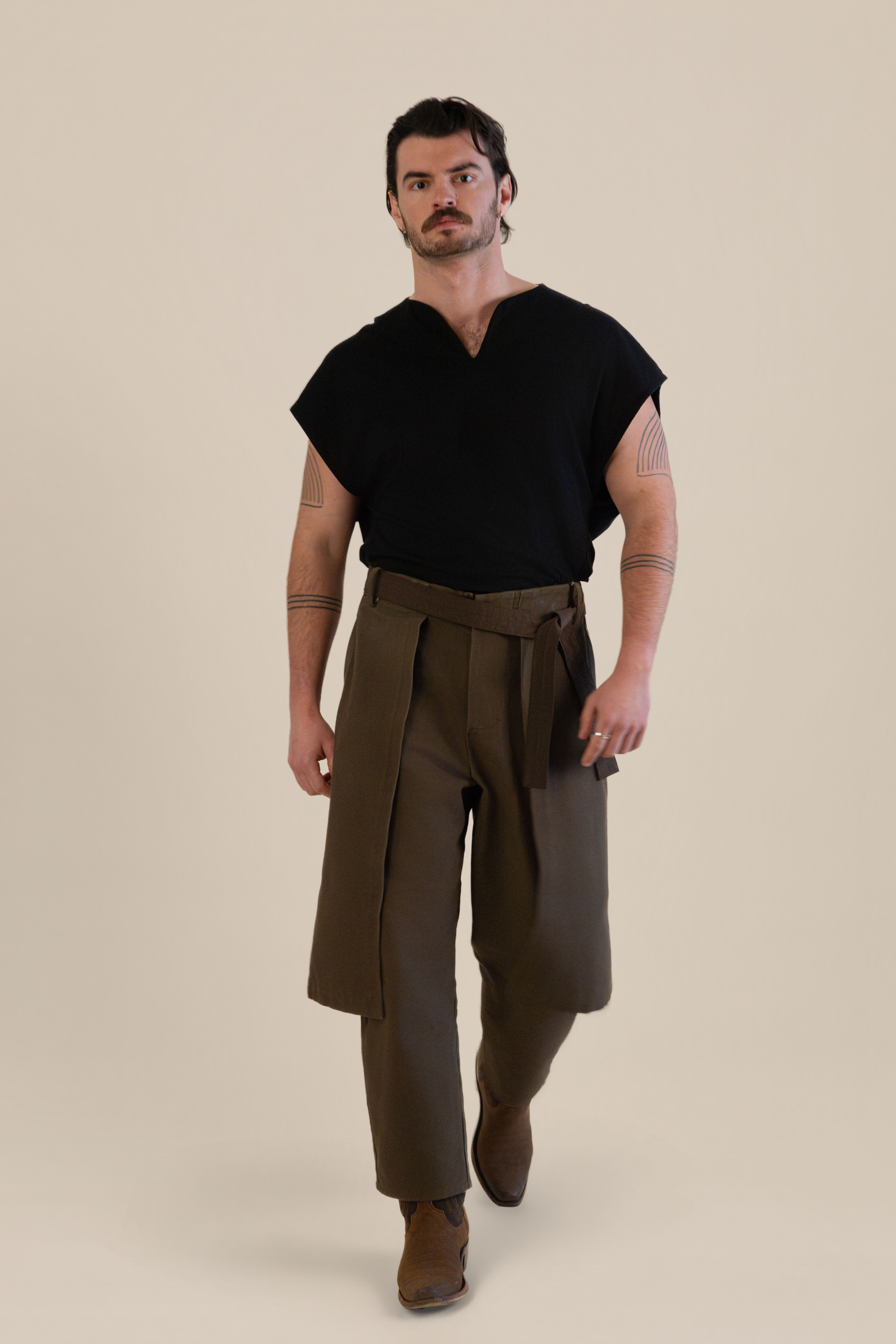 Back view of male model wearing brown Cowboy Pants in soft warm light, Oniri editorial aesthetic