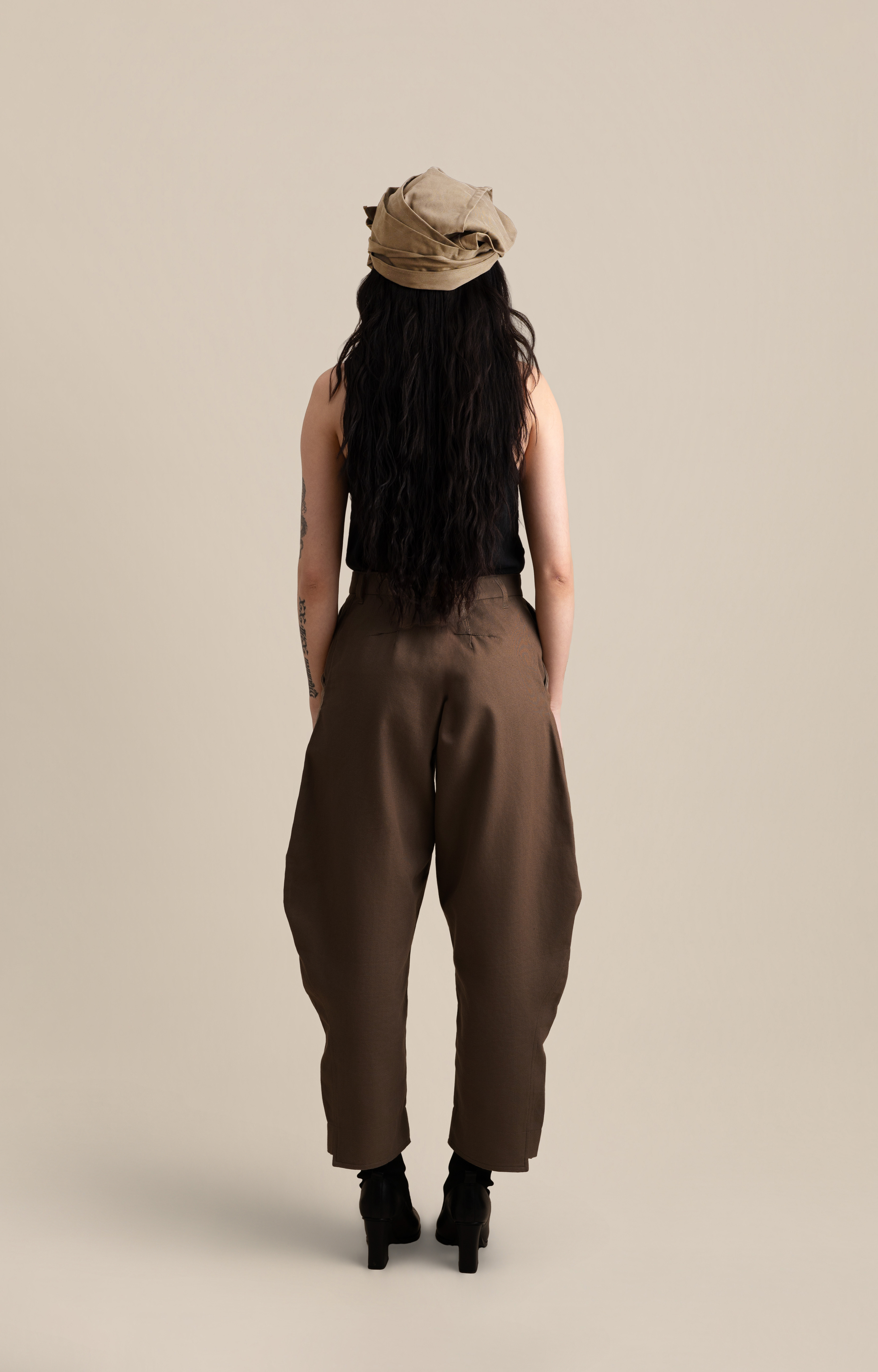 Back view of female model wearing the Light U-neck Tunic in white with grey twisted bandana, soft warm light, Oniri editorial aesthetic