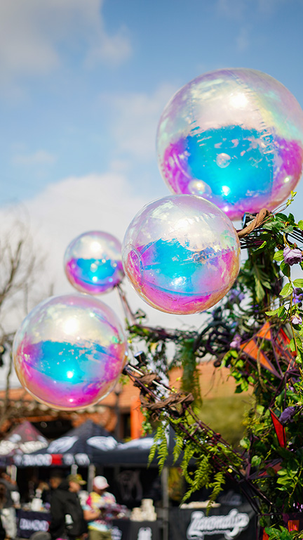 Colorful iridescent balloons displayed outdoors at a Wizard Trees event.