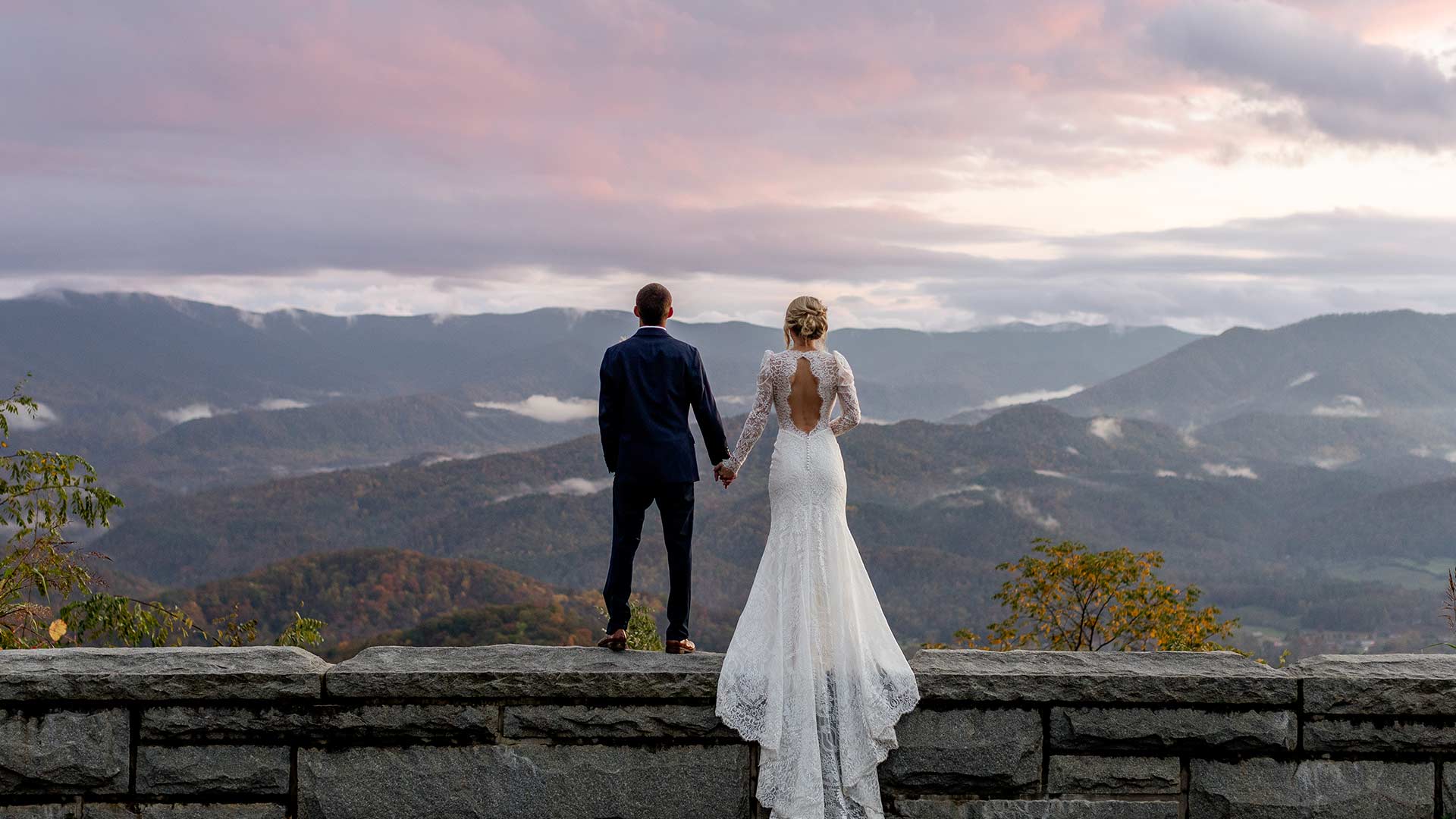 Bride and groom holding hands in Foothills Parkway with a view of the Smoky Mountains in the background.