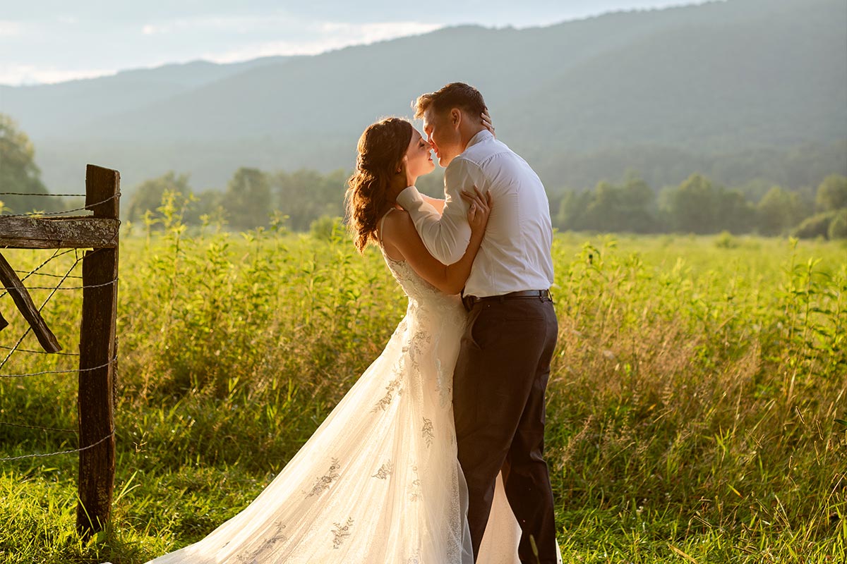 Photograph by Let's Elope Gatlinburg of a couple who eloped in the Smoky Mountains in Cades Cove with the mountains and sunlight in the background.