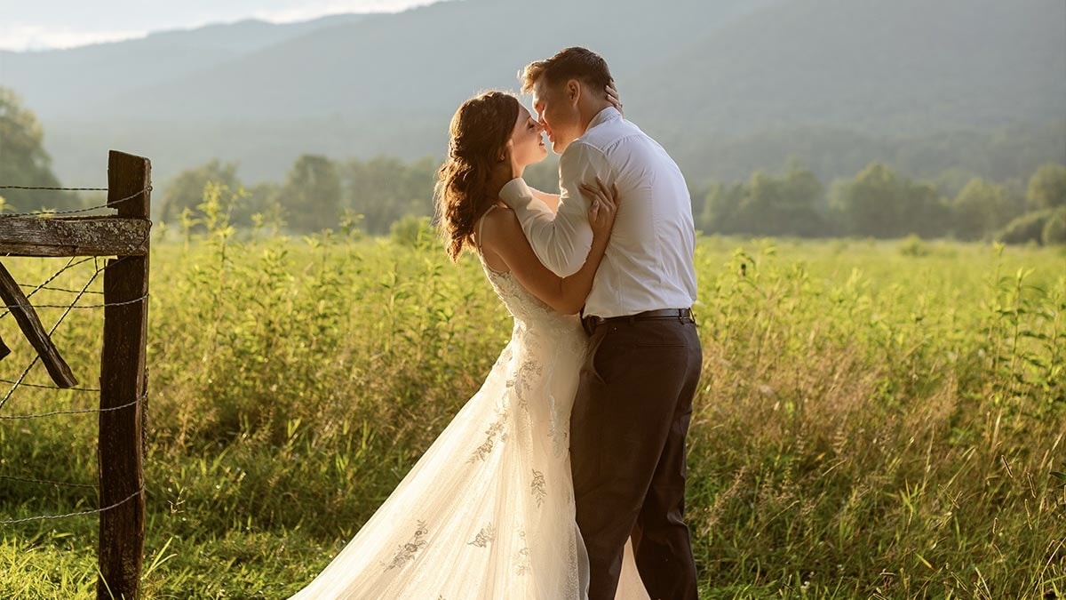 Photograph by Let's Elope Gatlinburg of a couple who eloped in the Smoky Mountains in Cades Cove with the mountains and sunlight in the background.