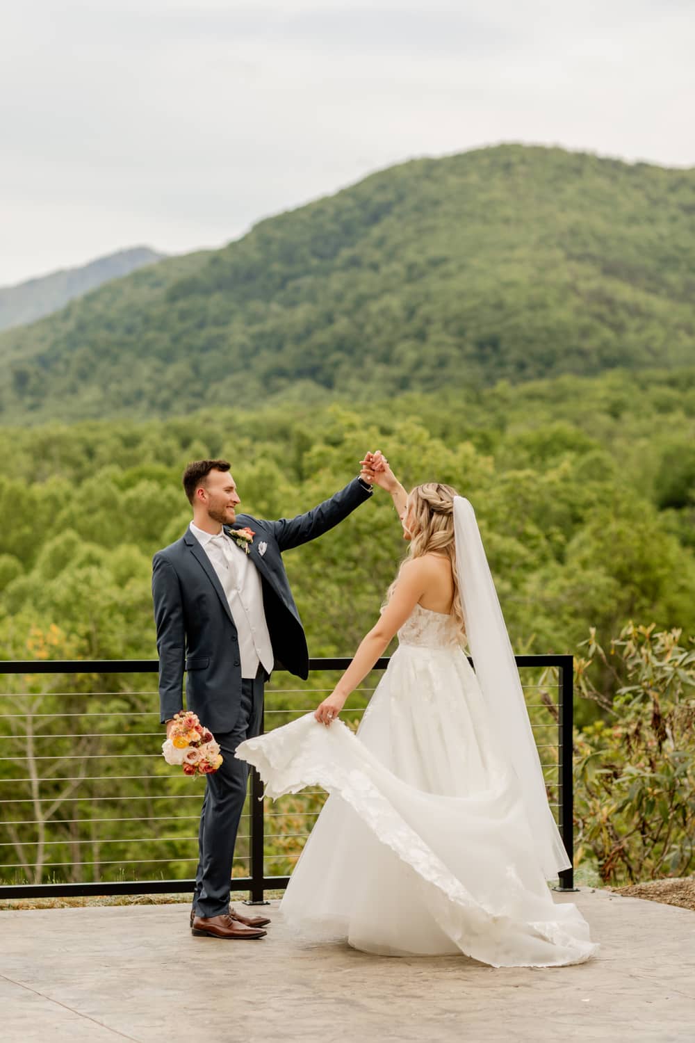 A couple celebrates their elopement with a scenic mountain backdrop in Gatlinburg, surrounded by lush greenery.