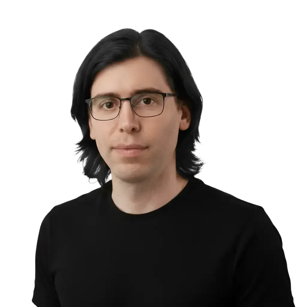 Man with medium-length black hair and glasses wearing a black shirt, facing forward with a neutral expression.