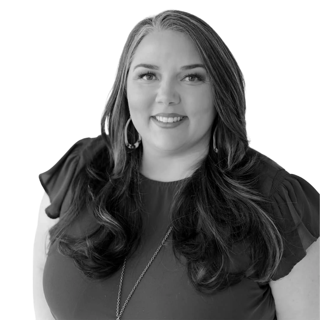 Smiling woman with long wavy hair wearing hoop earrings and a dark blouse.