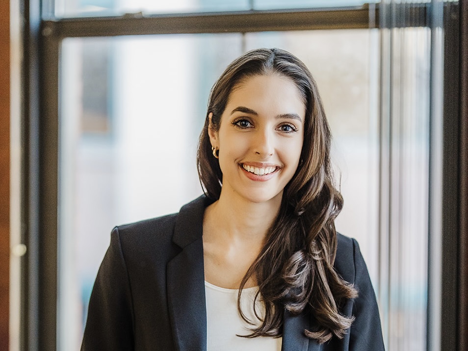 Hayley MacKenzie, Executive Director and Co-Founder at MHJP, smiling warmly with long dark hair, wearing a blazer against an office background.
